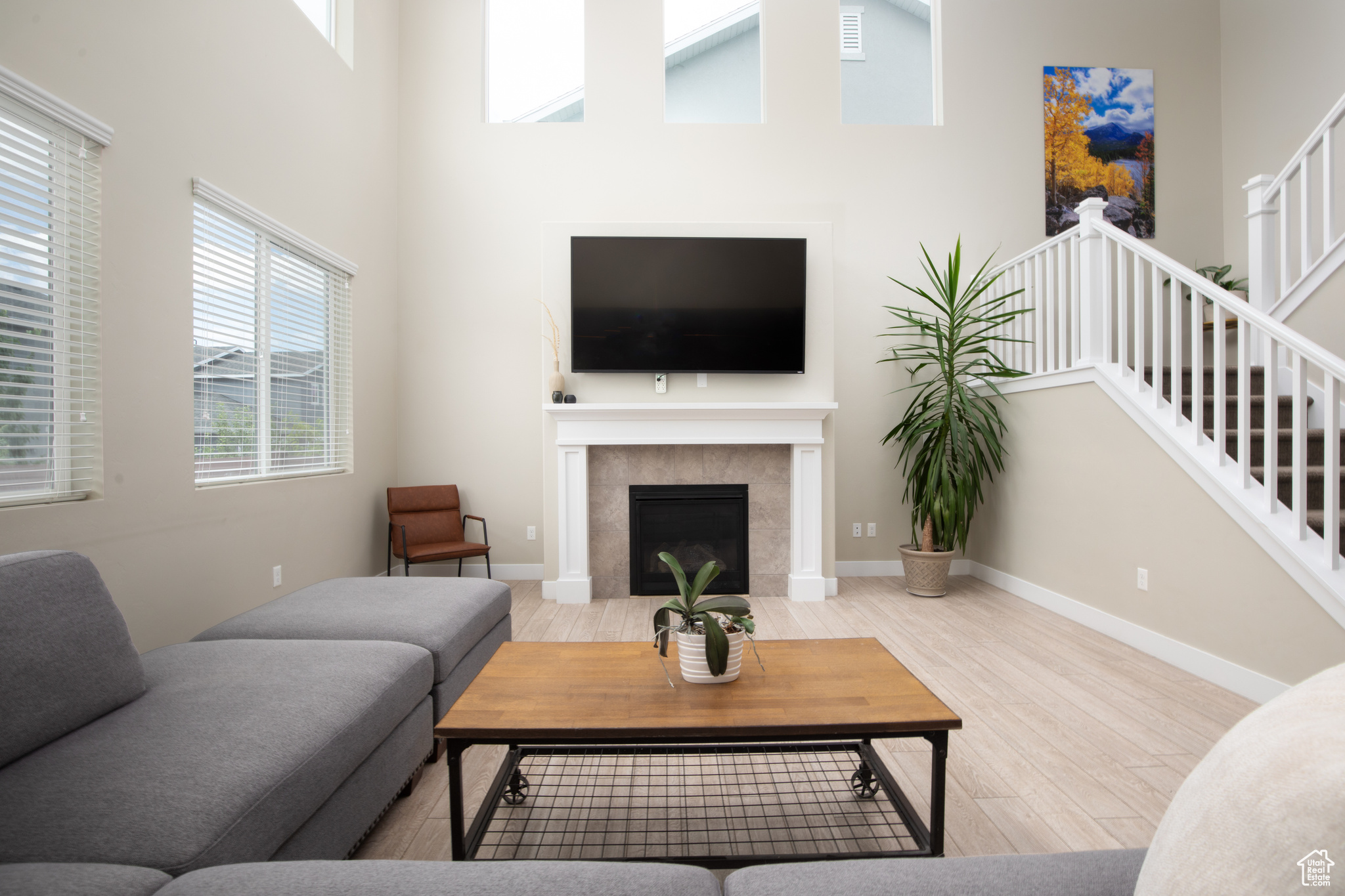 Living room featuring a towering ceiling, and tiled fireplace