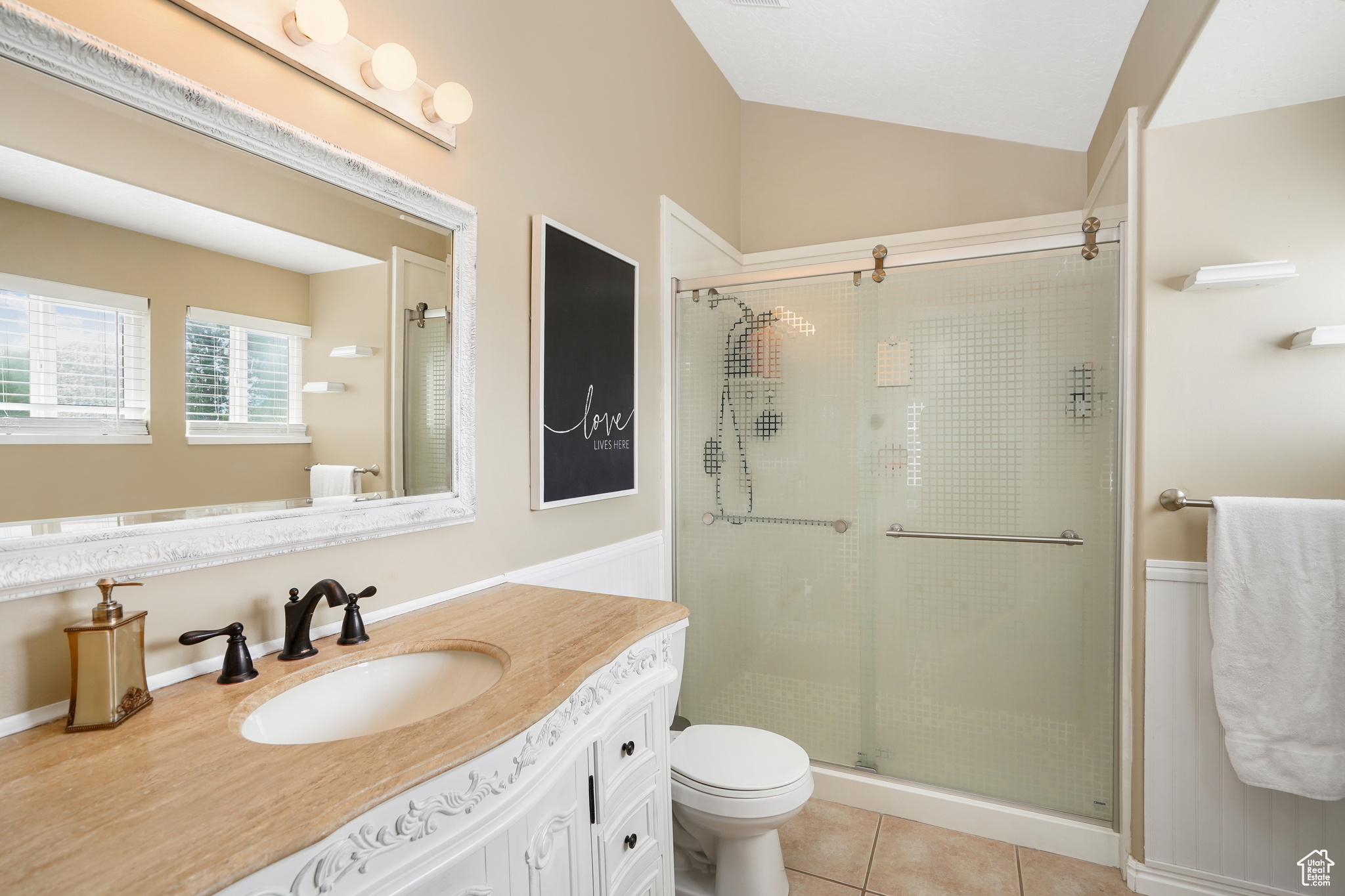 Bathroom with tile flooring, a shower with shower door, lofted ceiling, toilet, and vanity