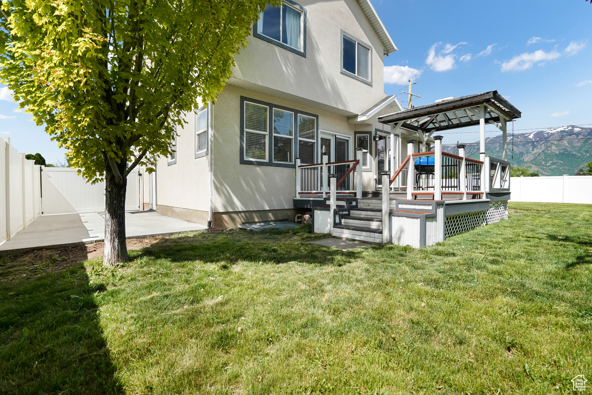 Back of house with a wooden deck and a lawn