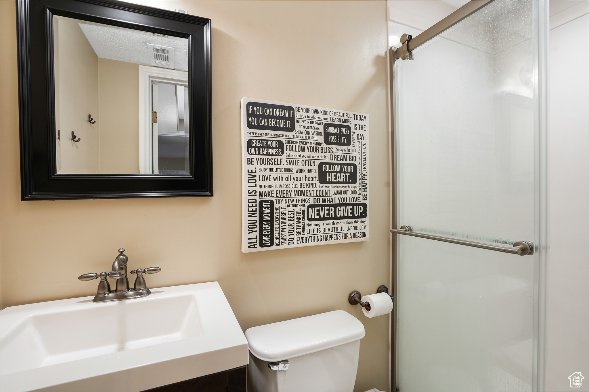 Bathroom featuring sink, an enclosed shower, and toilet