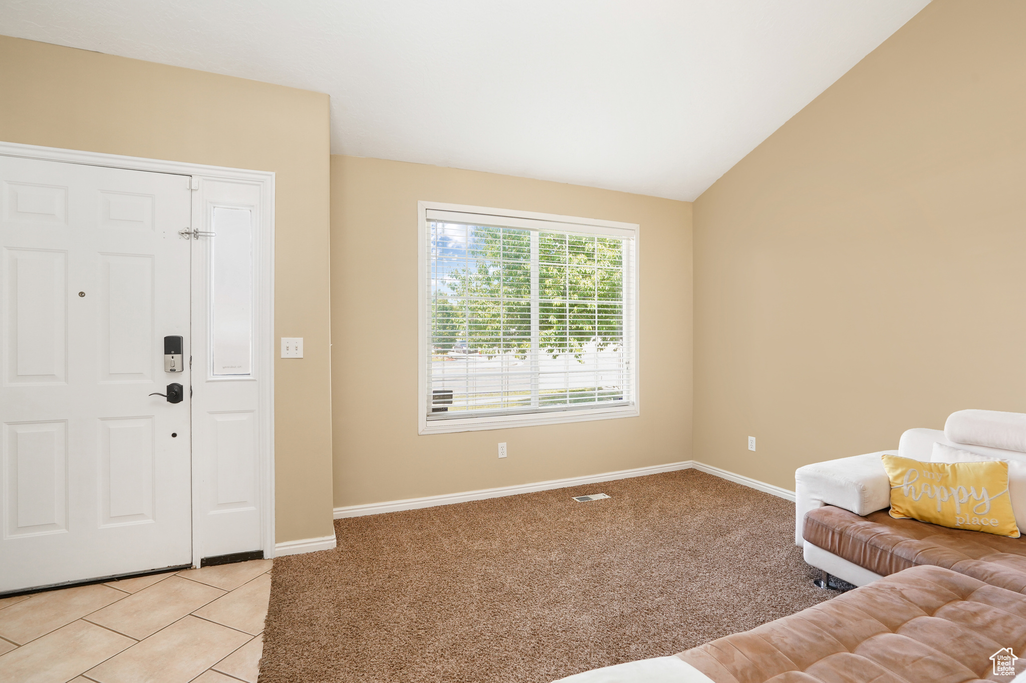 Carpeted foyer with vaulted ceiling