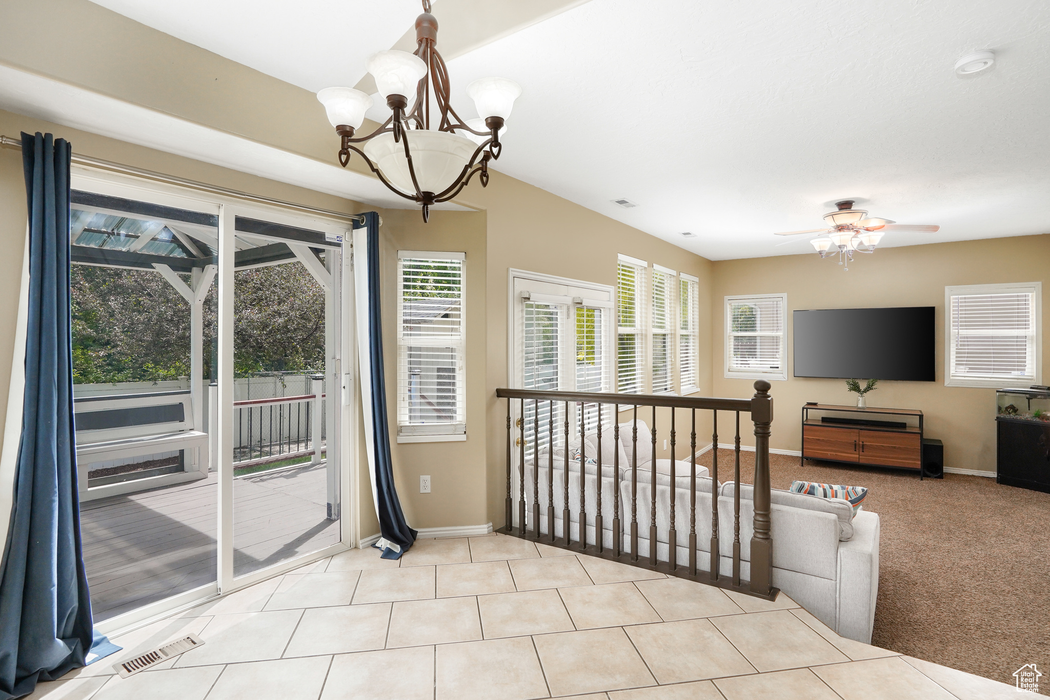 Interior space featuring light tile floors and ceiling fan with notable chandelier