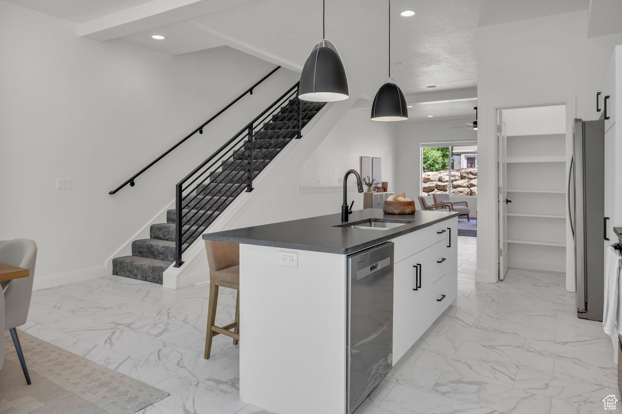 Kitchen with appliances with stainless steel finishes, white cabinets, a kitchen island with sink, sink, and light tile floors