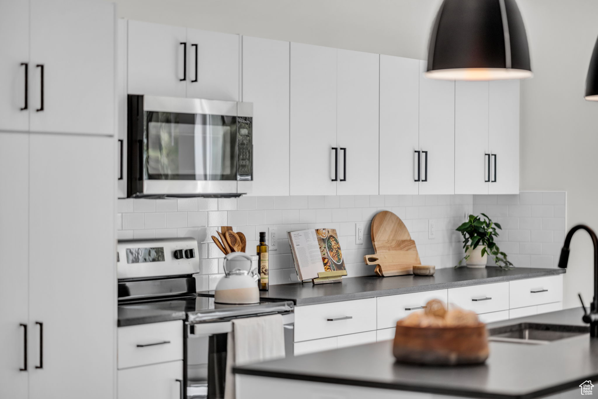 Kitchen with backsplash, appliances with stainless steel finishes, white cabinetry, and sink