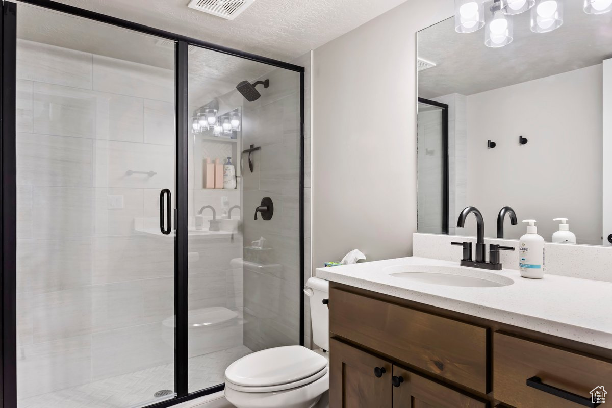 Bathroom with walk in shower, toilet, a textured ceiling, and large vanity