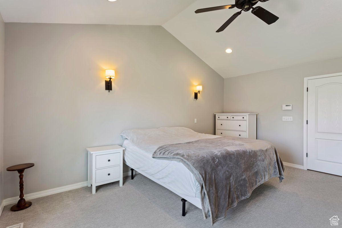 Carpeted bedroom featuring ceiling fan and lofted ceiling