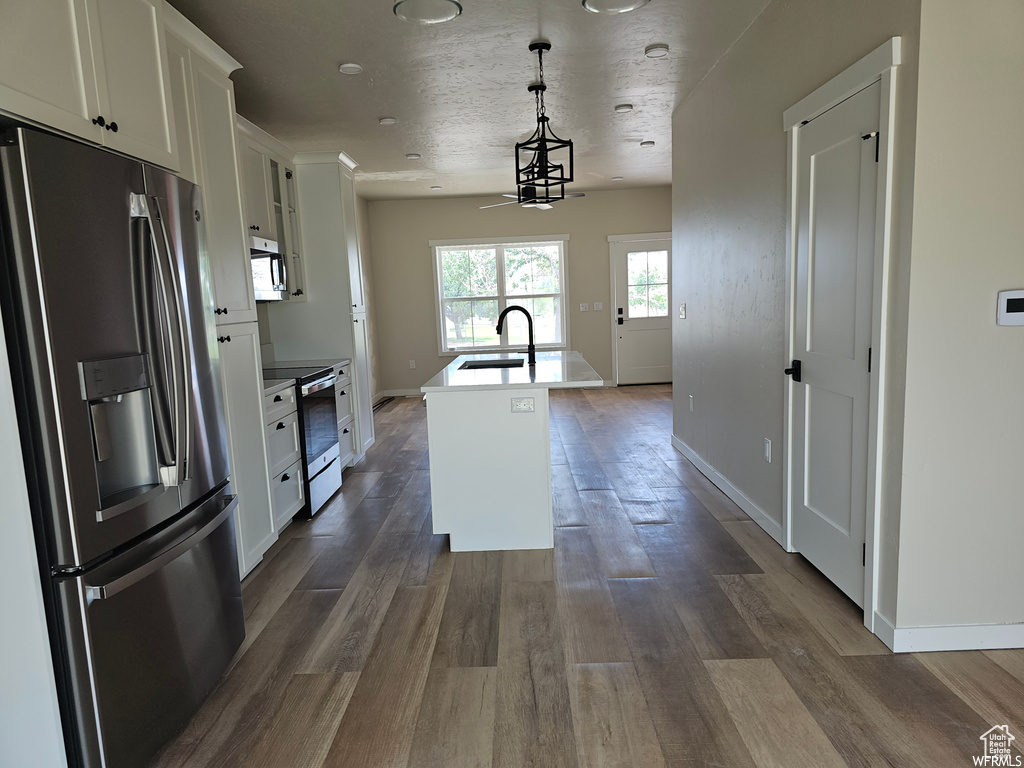 Kitchen with an island with sink, pendant lighting, dark hardwood / wood-style flooring, sink, and appliances with stainless steel finishes