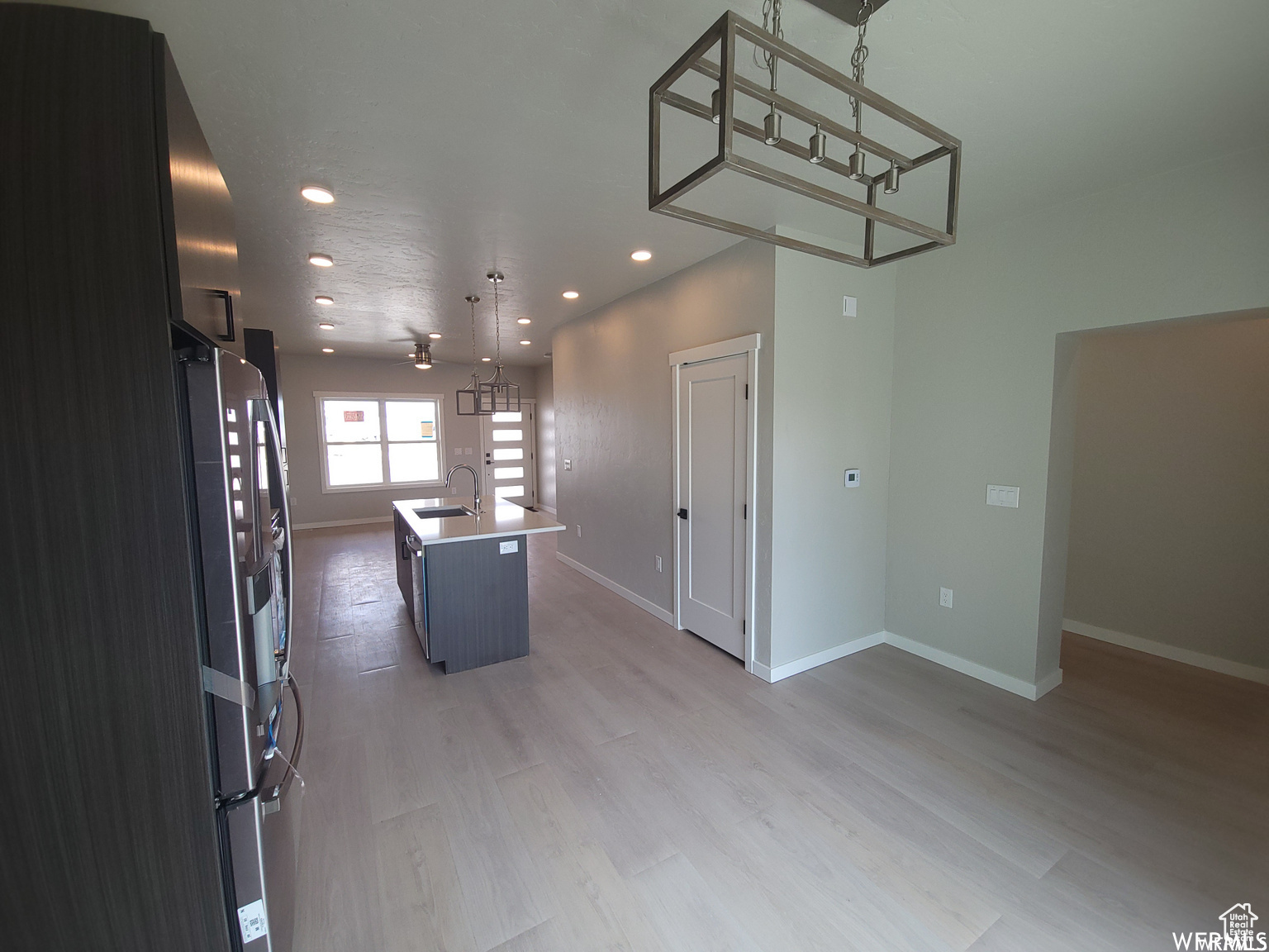 Kitchen featuring sink, a kitchen island with sink, light hardwood / wood-style floors, and hanging light fixtures