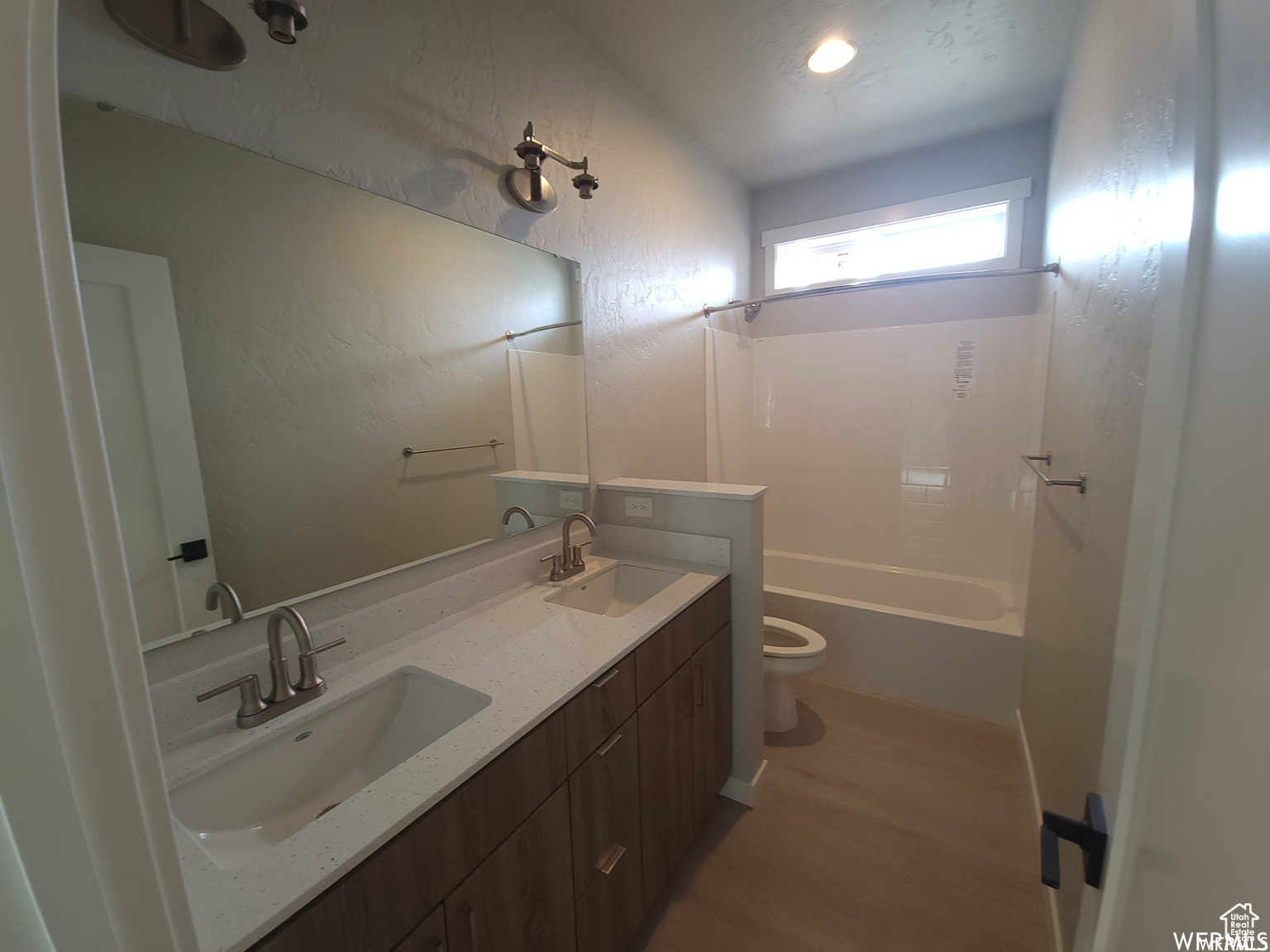 Full bathroom featuring double sink, bathing tub / shower combination, toilet, hardwood / wood-style floors, and oversized vanity