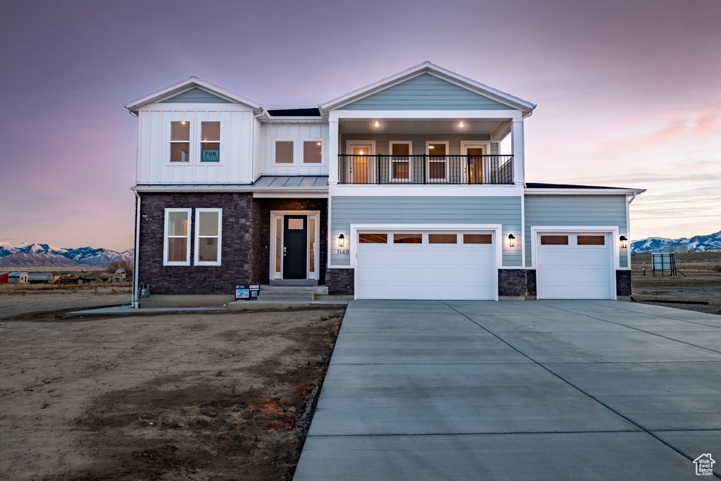 View of front of house featuring a mountain view, a balcony, and a garage