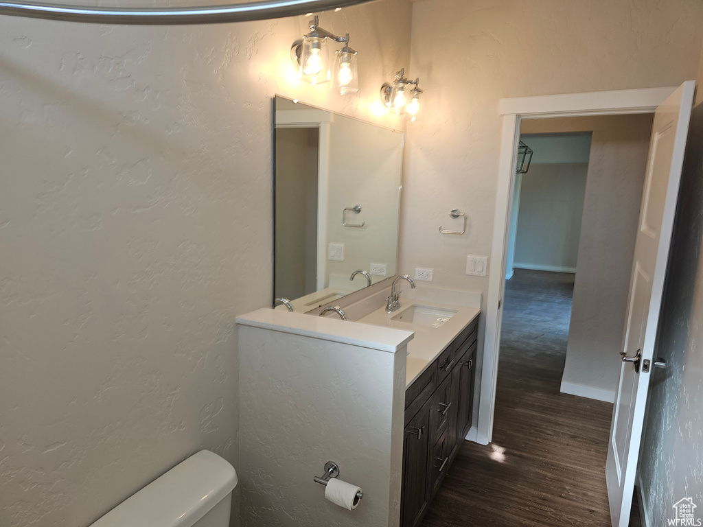 Bathroom featuring vanity with extensive cabinet space, hardwood / wood-style floors, and toilet