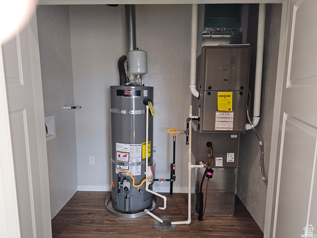 Utility room featuring strapped water heater