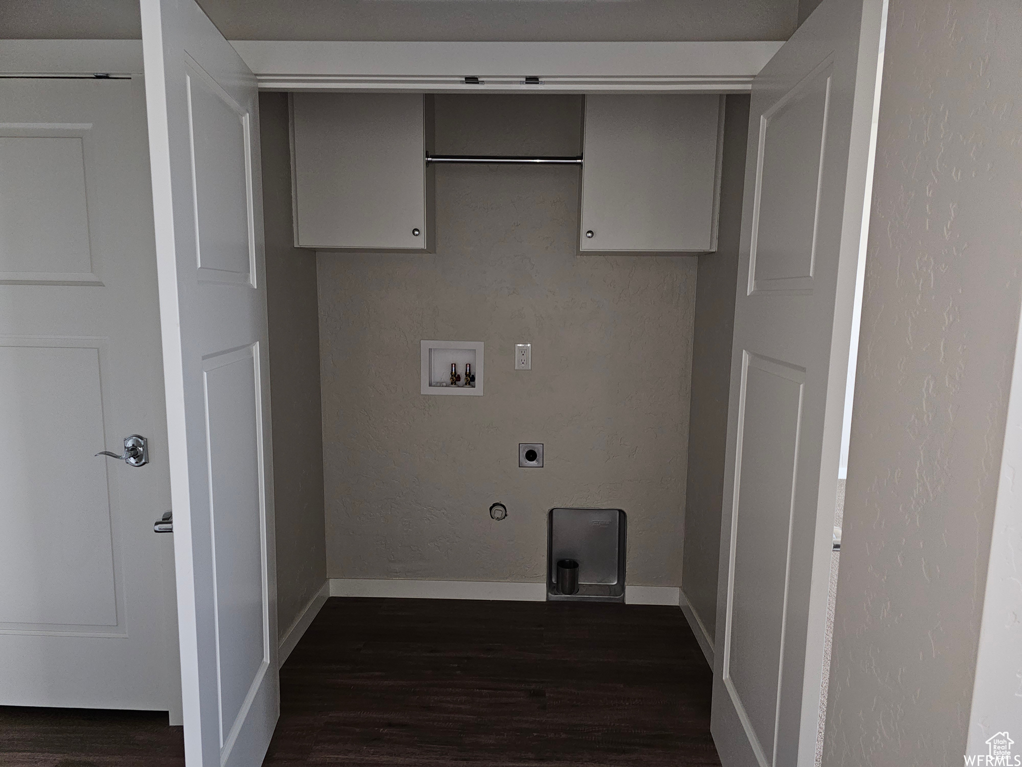 Laundry area with dark wood-type flooring, washer hookup, and hookup for an electric dryer