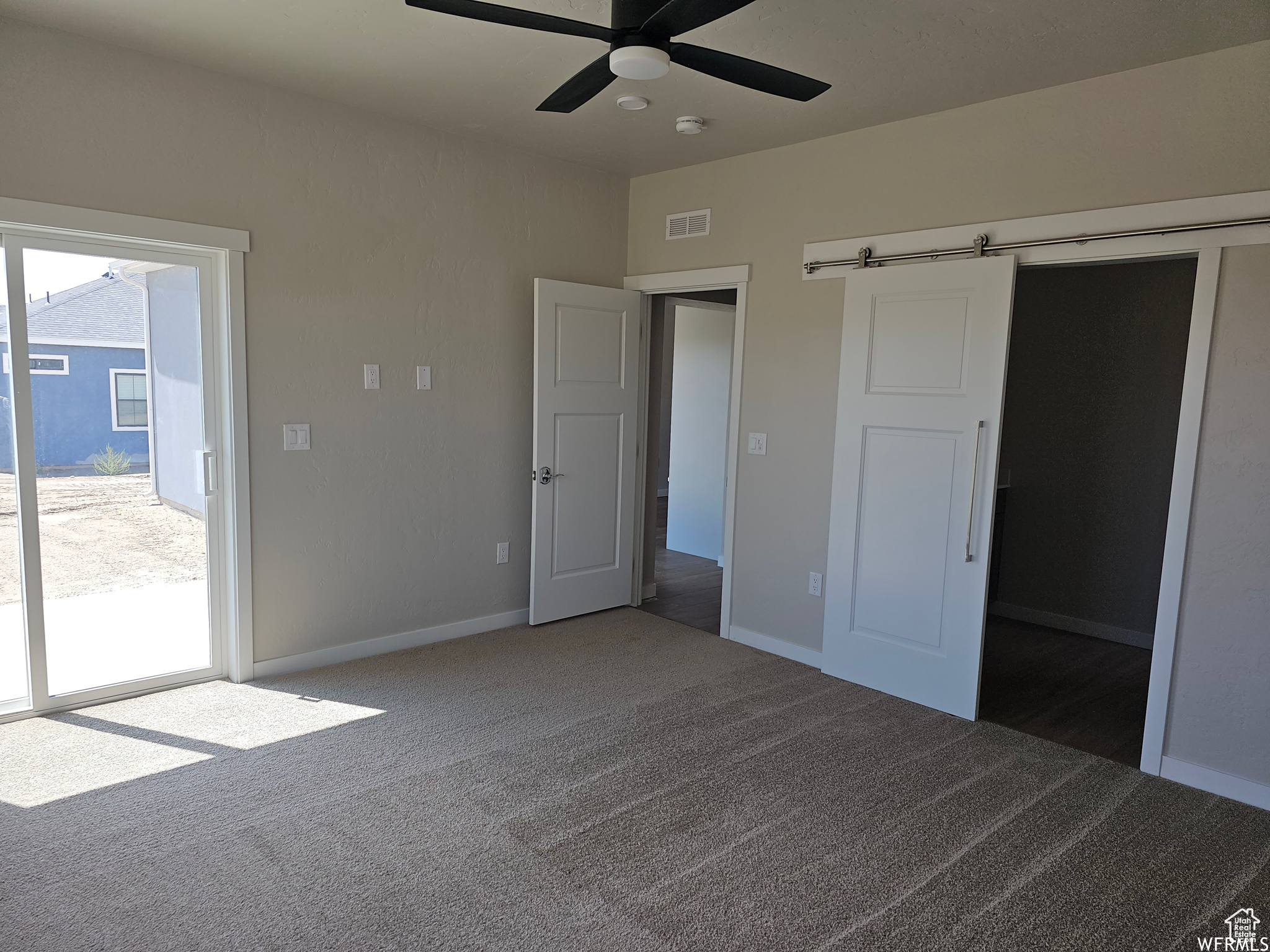 Unfurnished bedroom with ceiling fan, multiple windows, and dark carpet