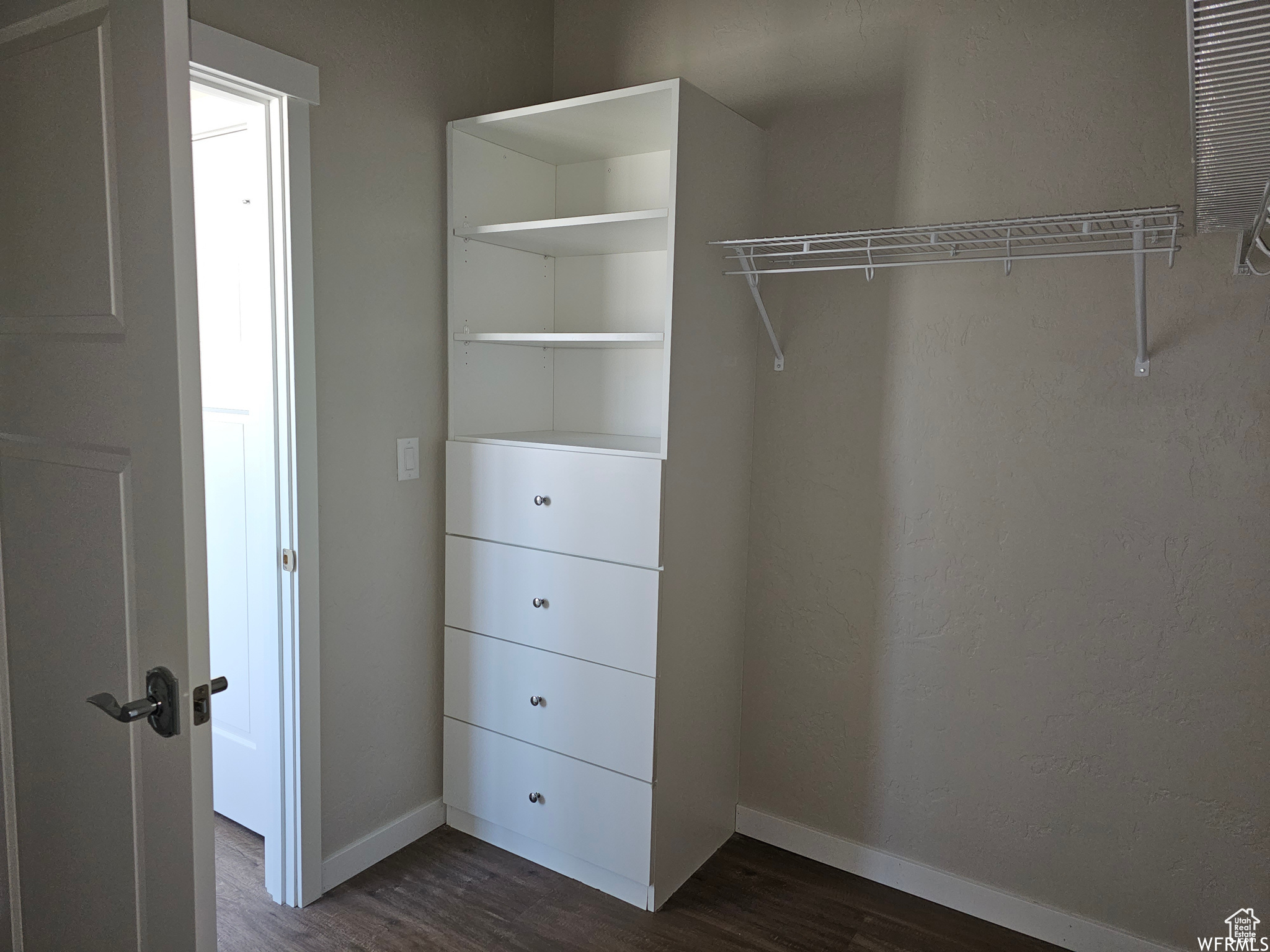 Walk in closet with dark hardwood / wood-style flooring