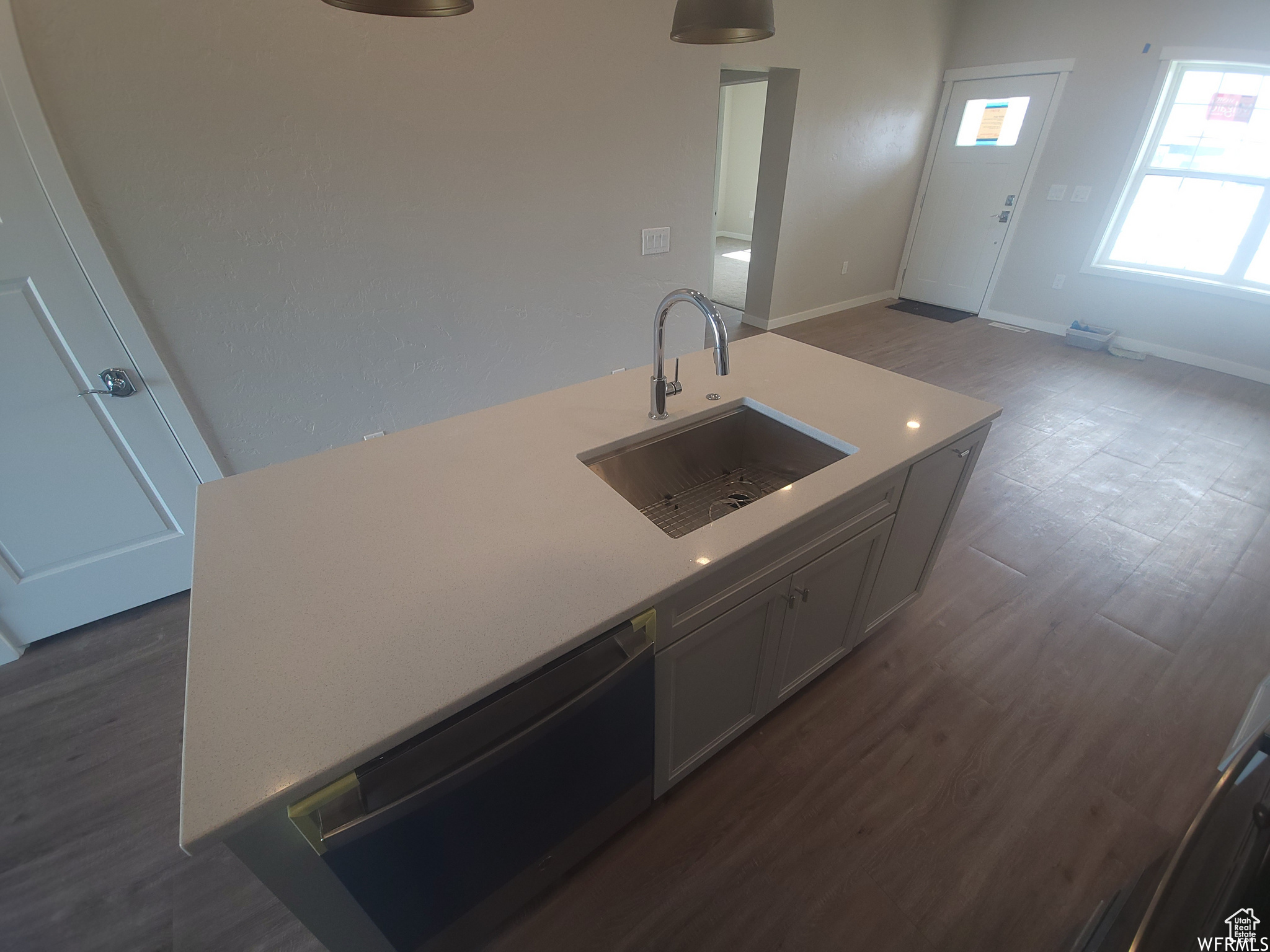 Kitchen featuring sink, black dishwasher, and dark wood-type flooring