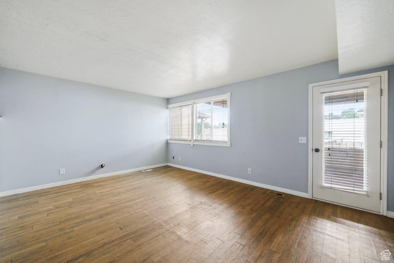 Spare room with a healthy amount of sunlight, a textured ceiling, and wood-type flooring