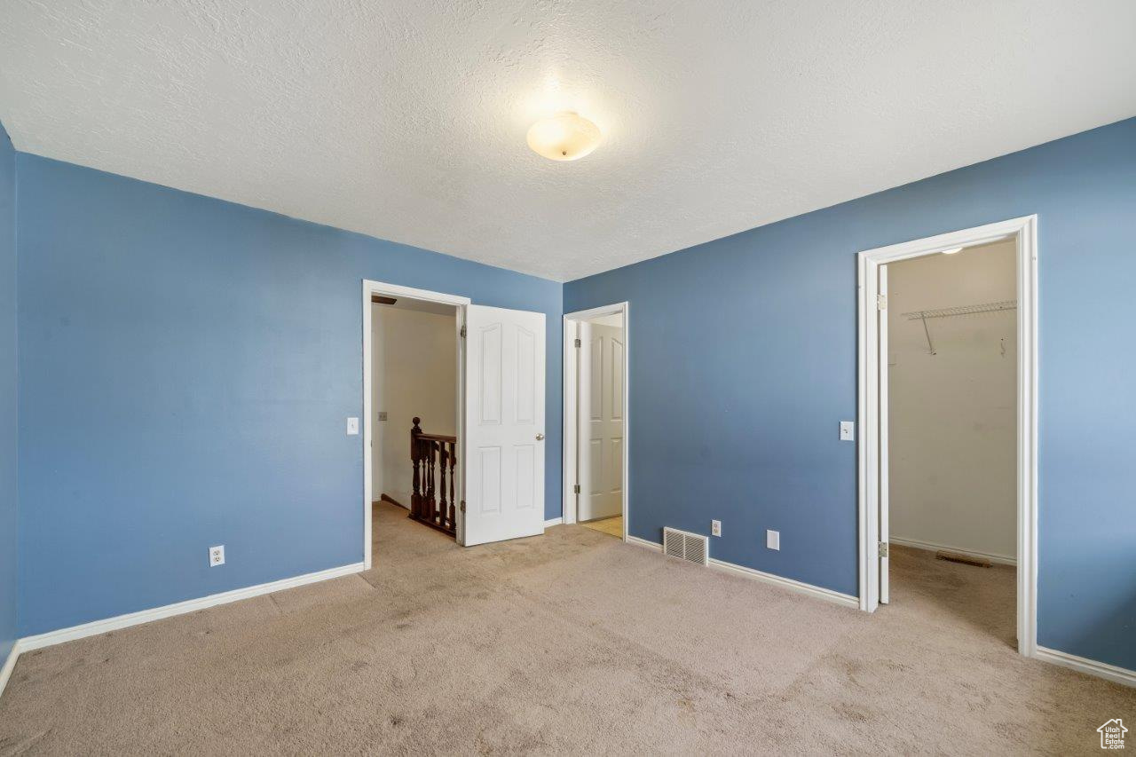 Bedroom featuring a closet, a textured ceiling, light carpet, and a spacious closet