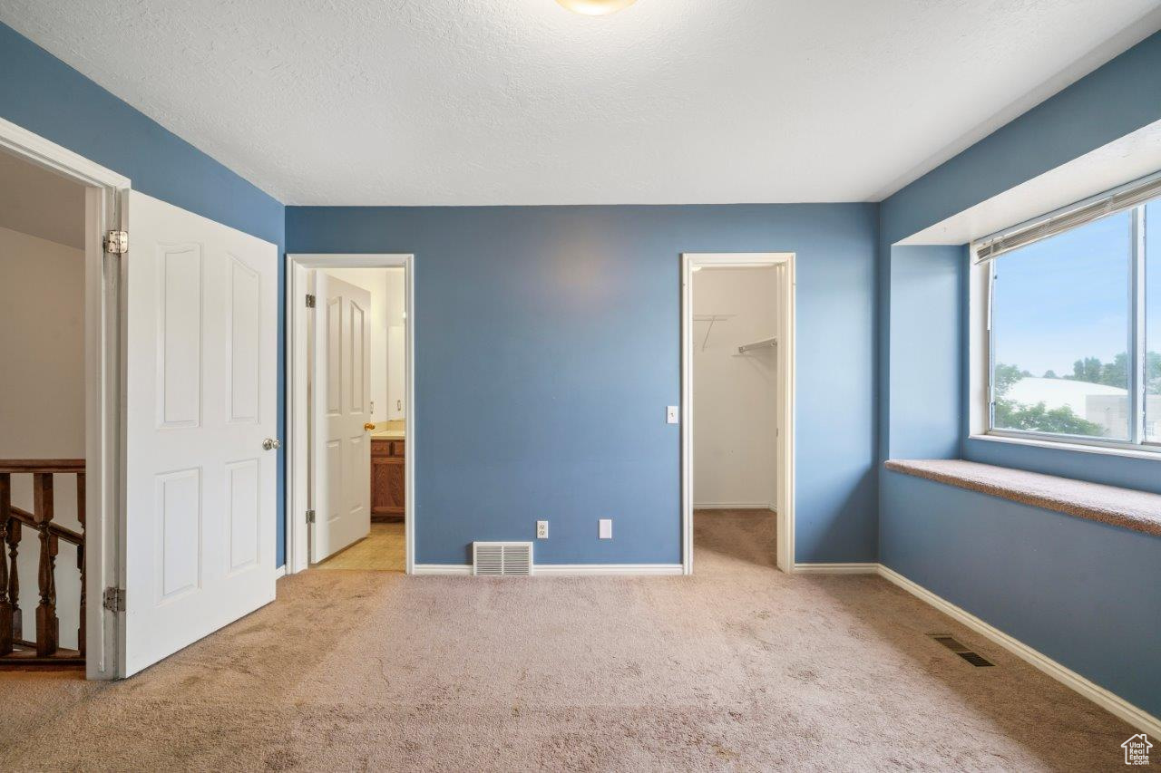 Bedroom with ensuite bath, a closet, light carpet, and a spacious closet