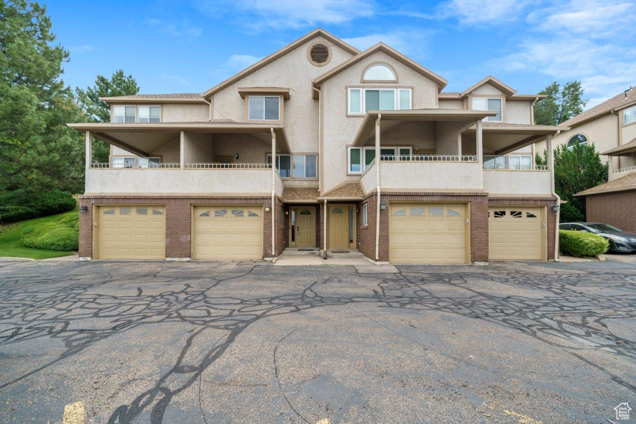 View of front of house with a garage and a balcony