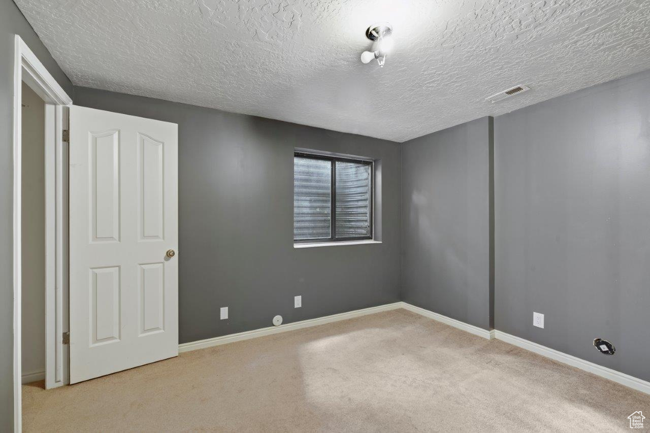 Bedroom with a textured ceiling and light carpet