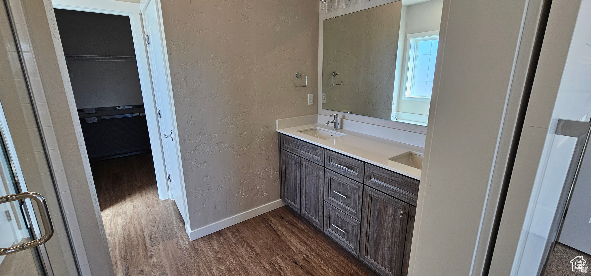 Bathroom with a shower with shower door, wood-type flooring, and double sink vanity