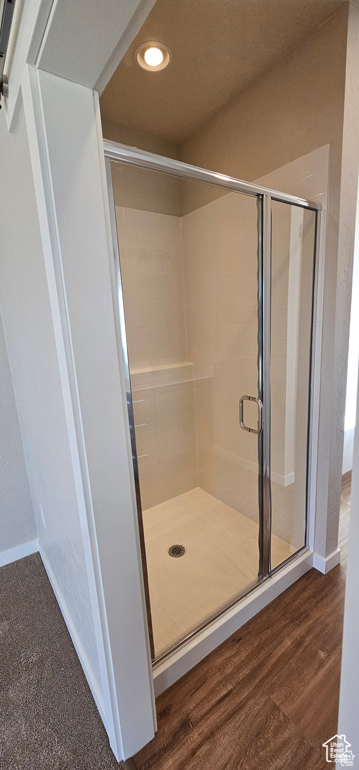 Bathroom with hardwood / wood-style floors and a shower with door