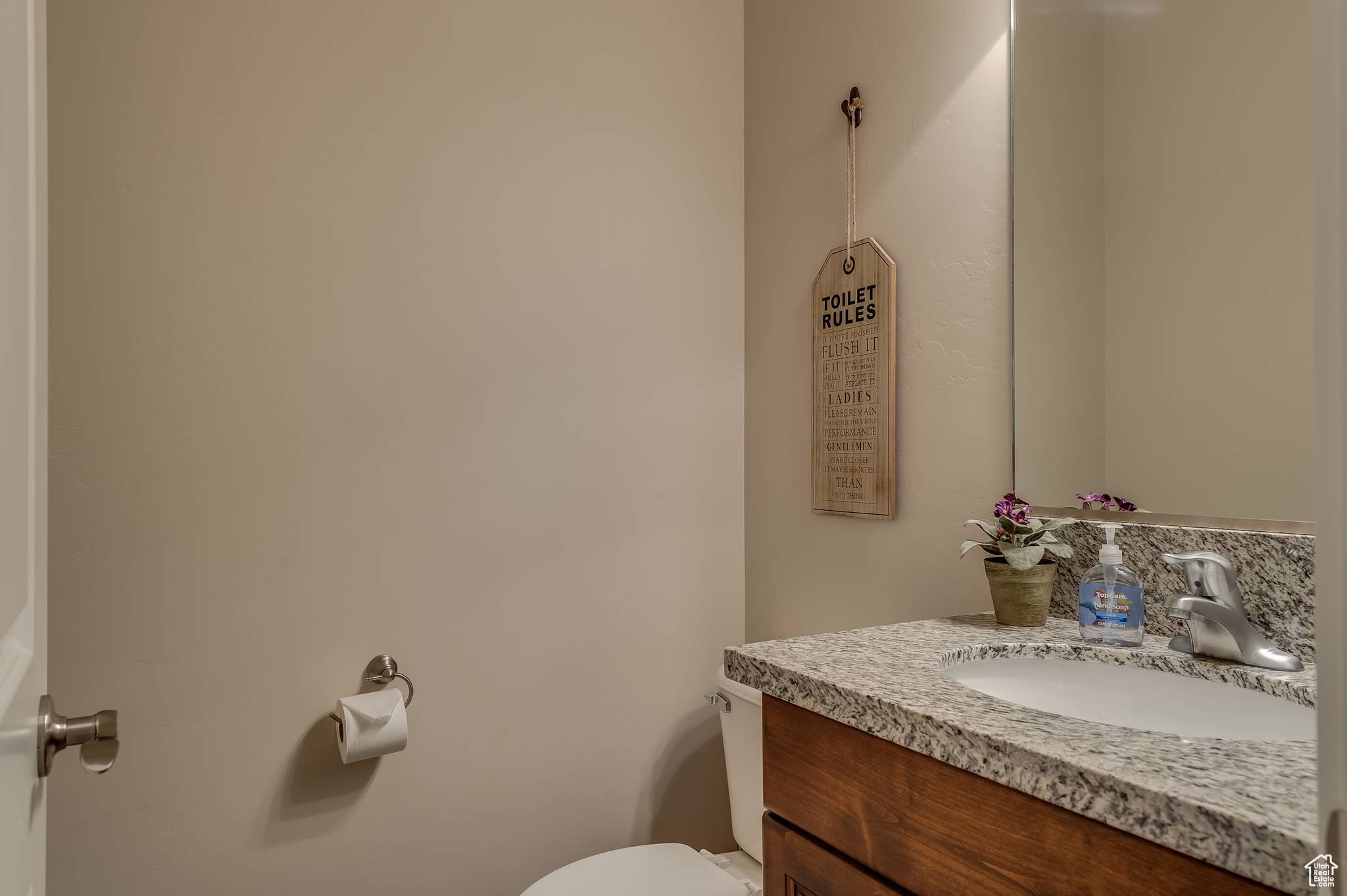 Half-bath featuring vanity and toilet adjacent to laundry room