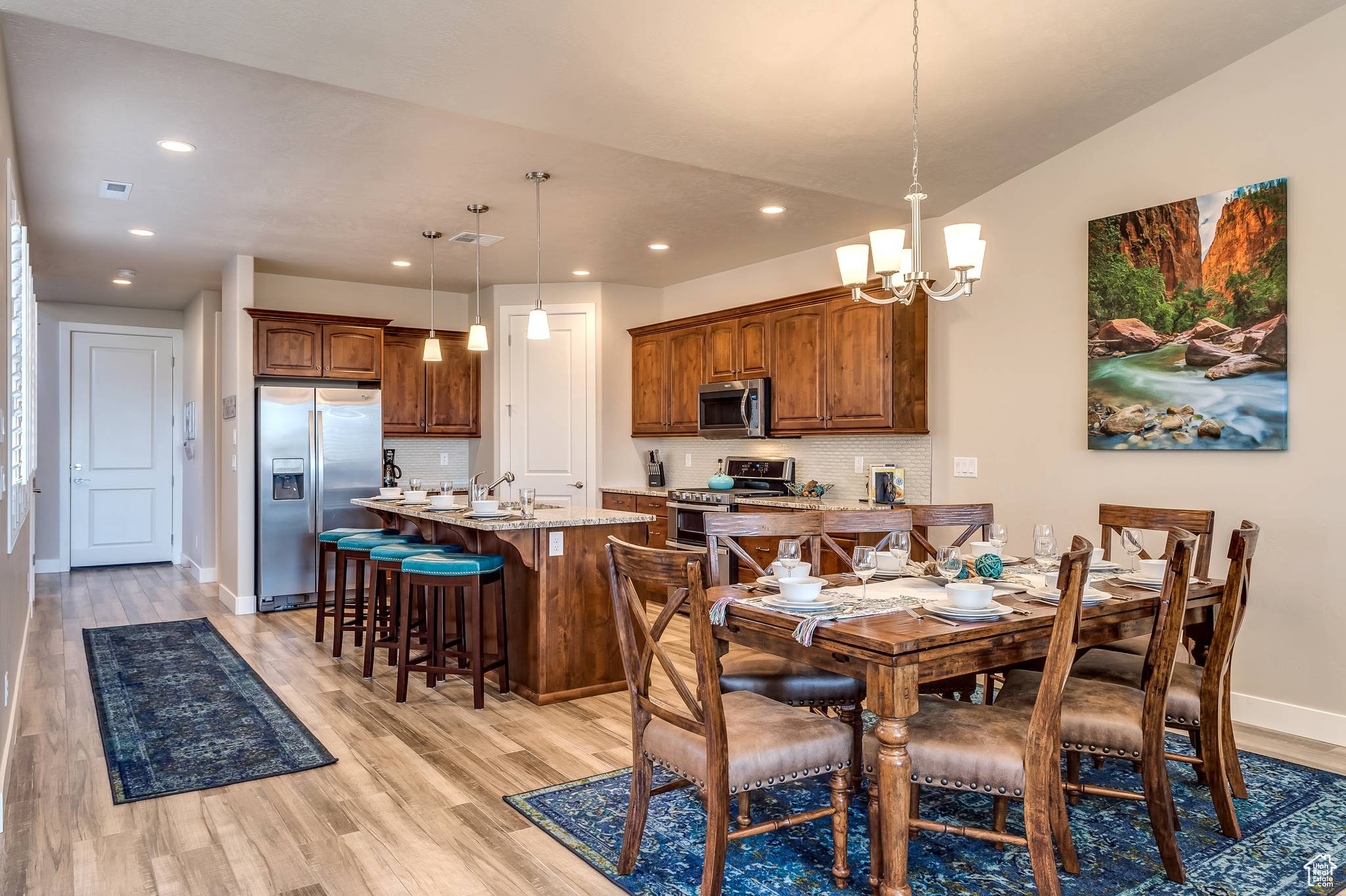 Dining area with vaulted ceiling, sink, a chandelier, and light hardwood / wood-style flooring