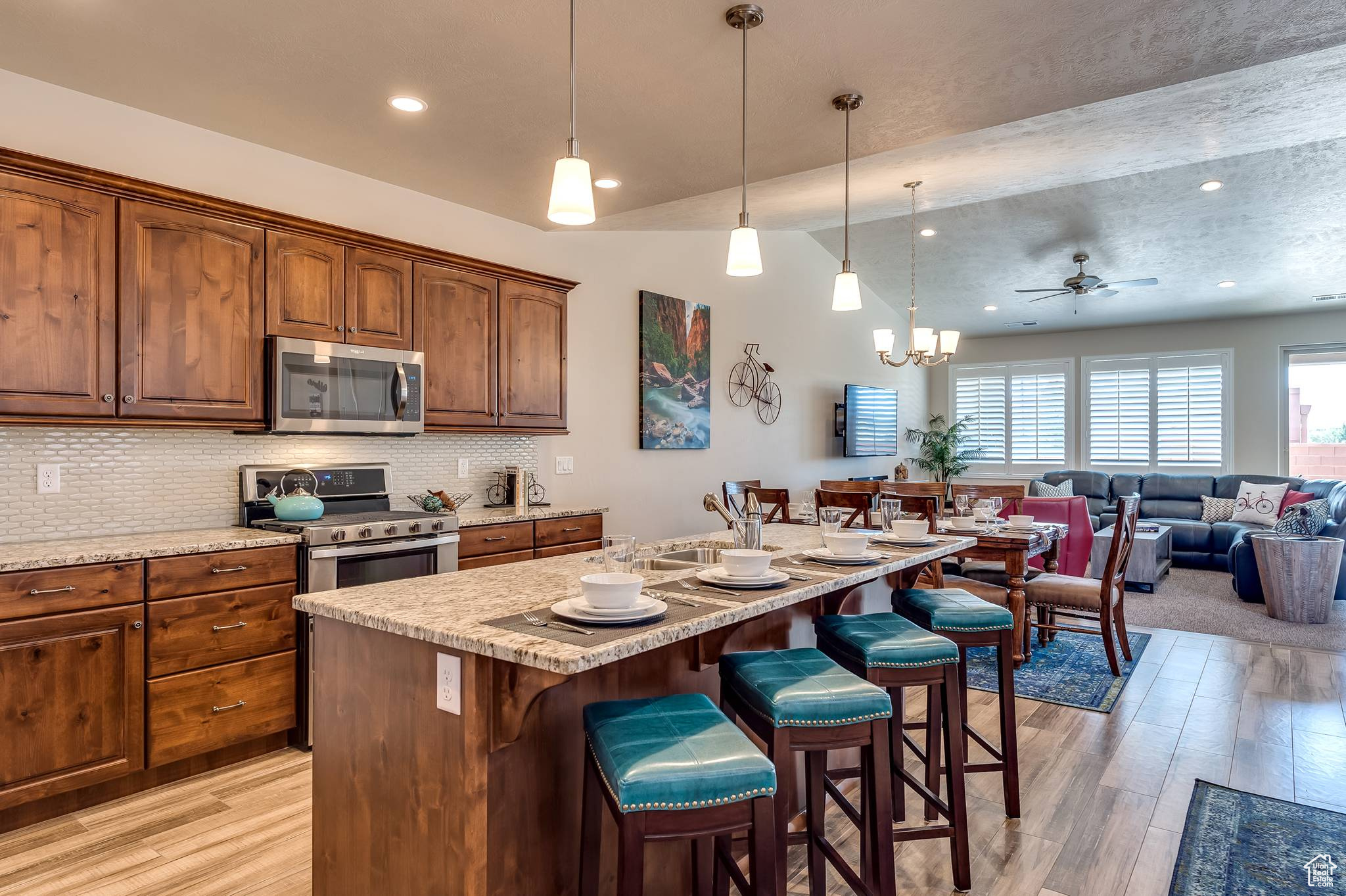 Kitchen with light hardwood / wood-style flooring, tasteful backsplash, an island with sink, a kitchen bar, and appliances with stainless steel finishes