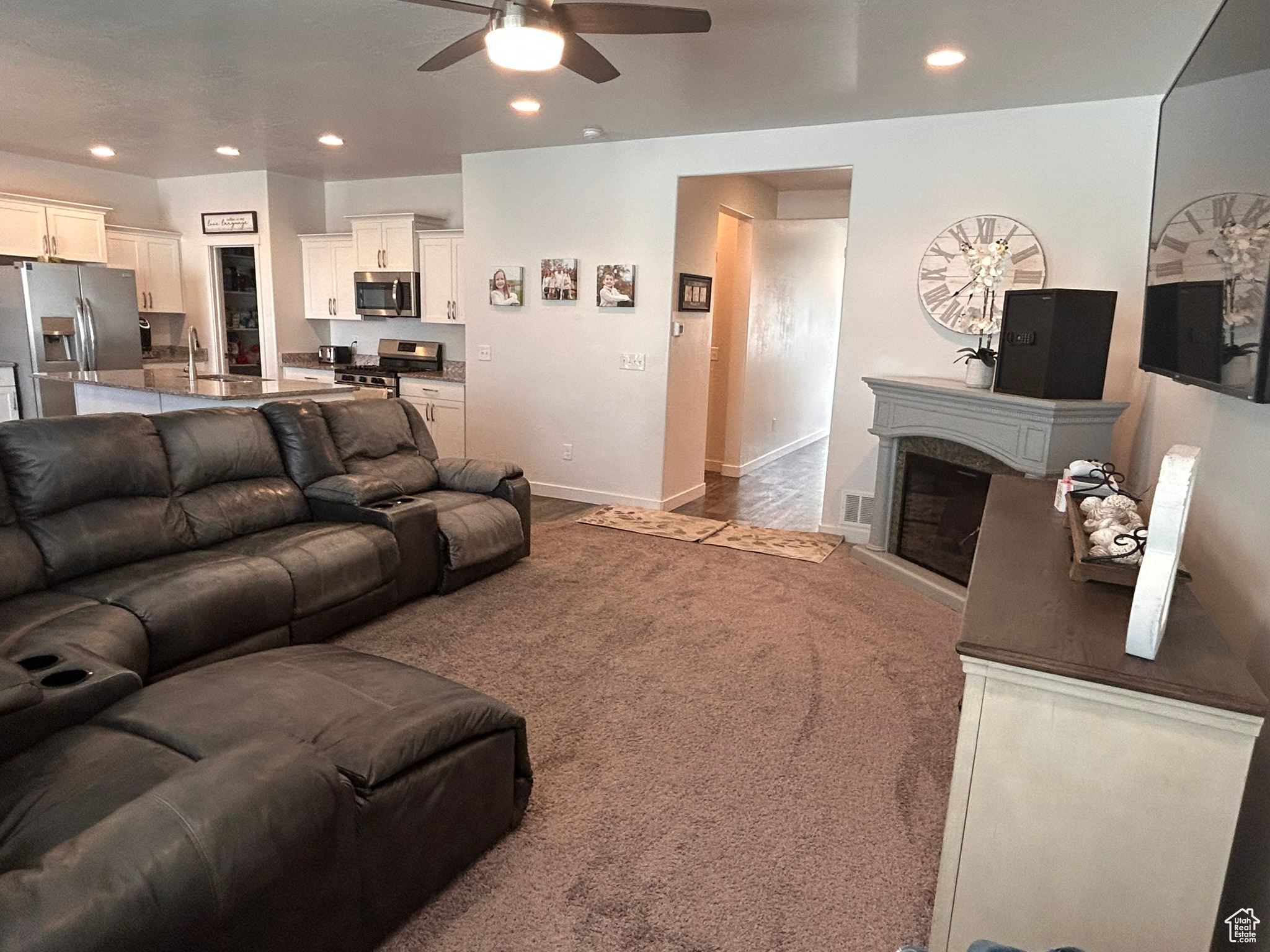 Carpeted living room featuring sink, ceiling fan, and a fireplace