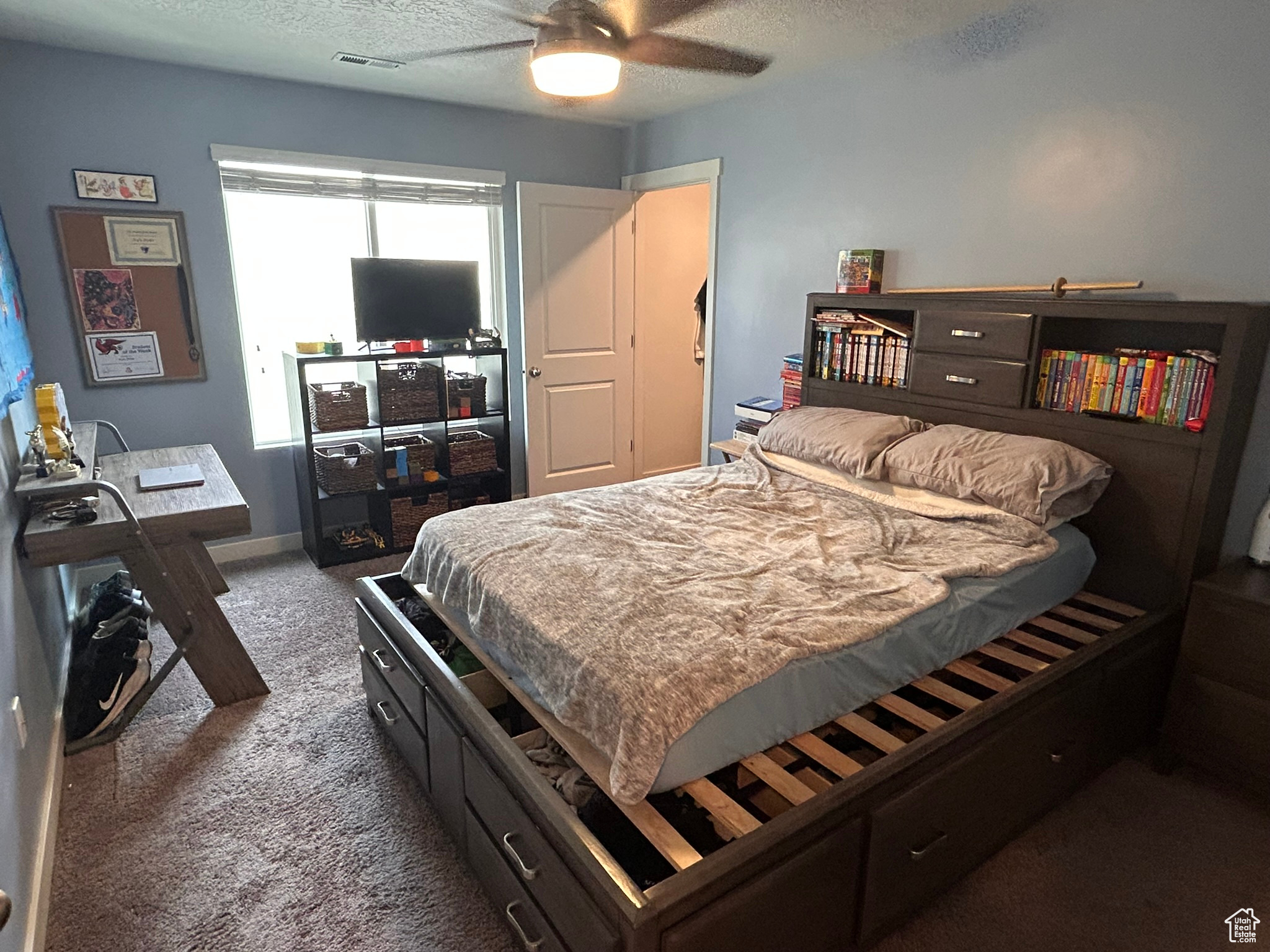 Carpeted bedroom with ceiling fan and a textured ceiling