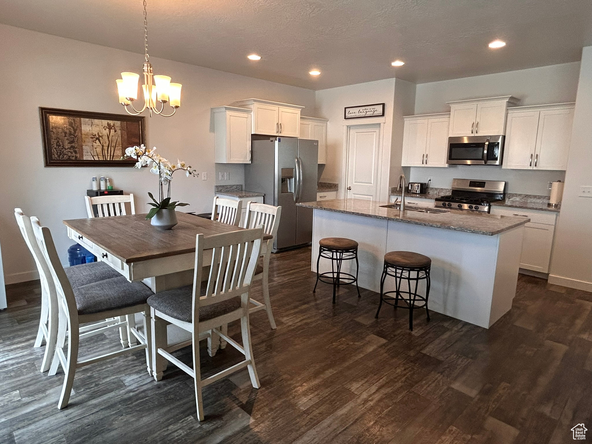 Kitchen with an island with sink, dark hardwood / wood-style flooring, and stainless steel appliances