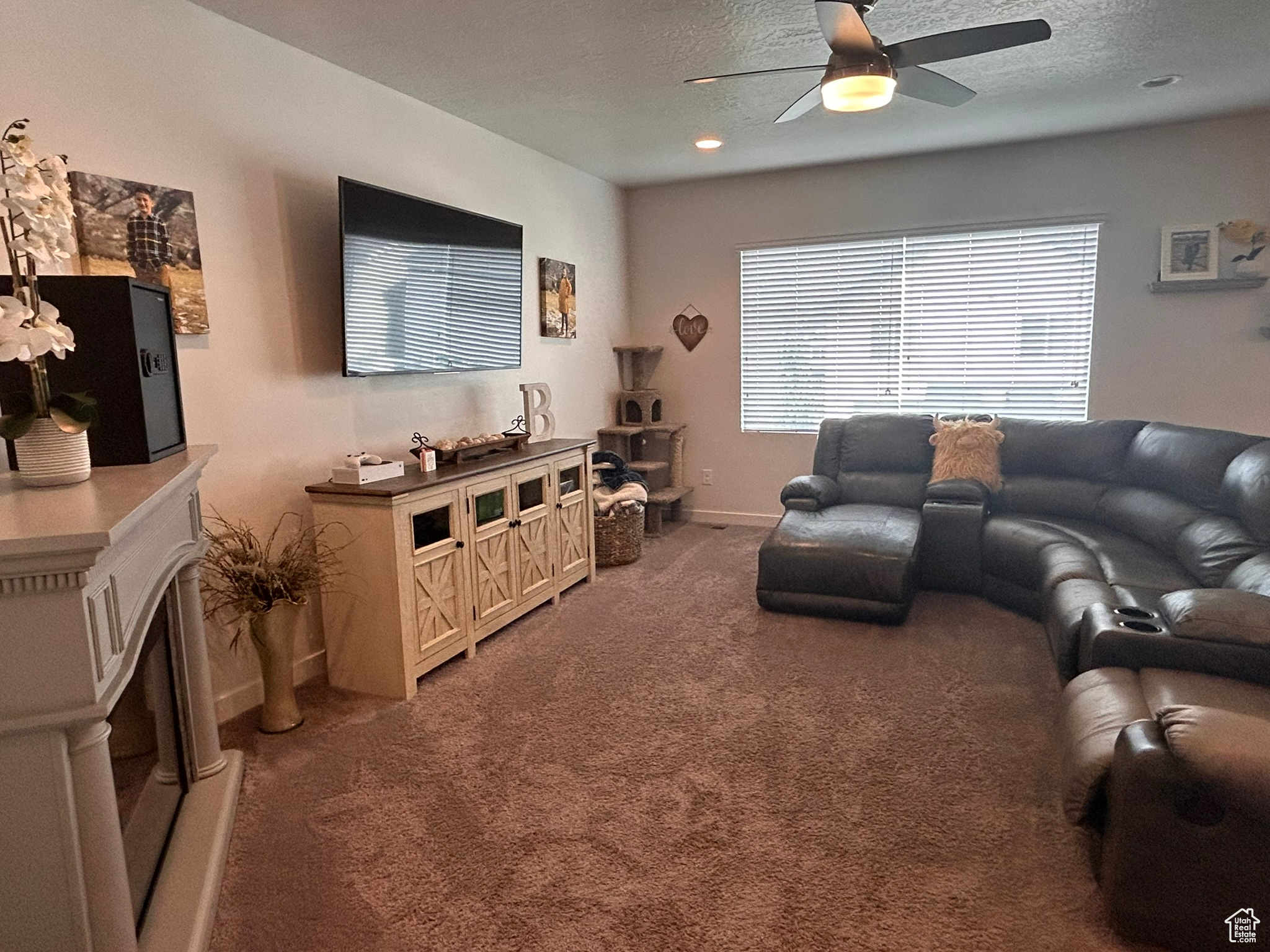 Living room featuring ceiling fan, carpet floors, and a textured ceiling