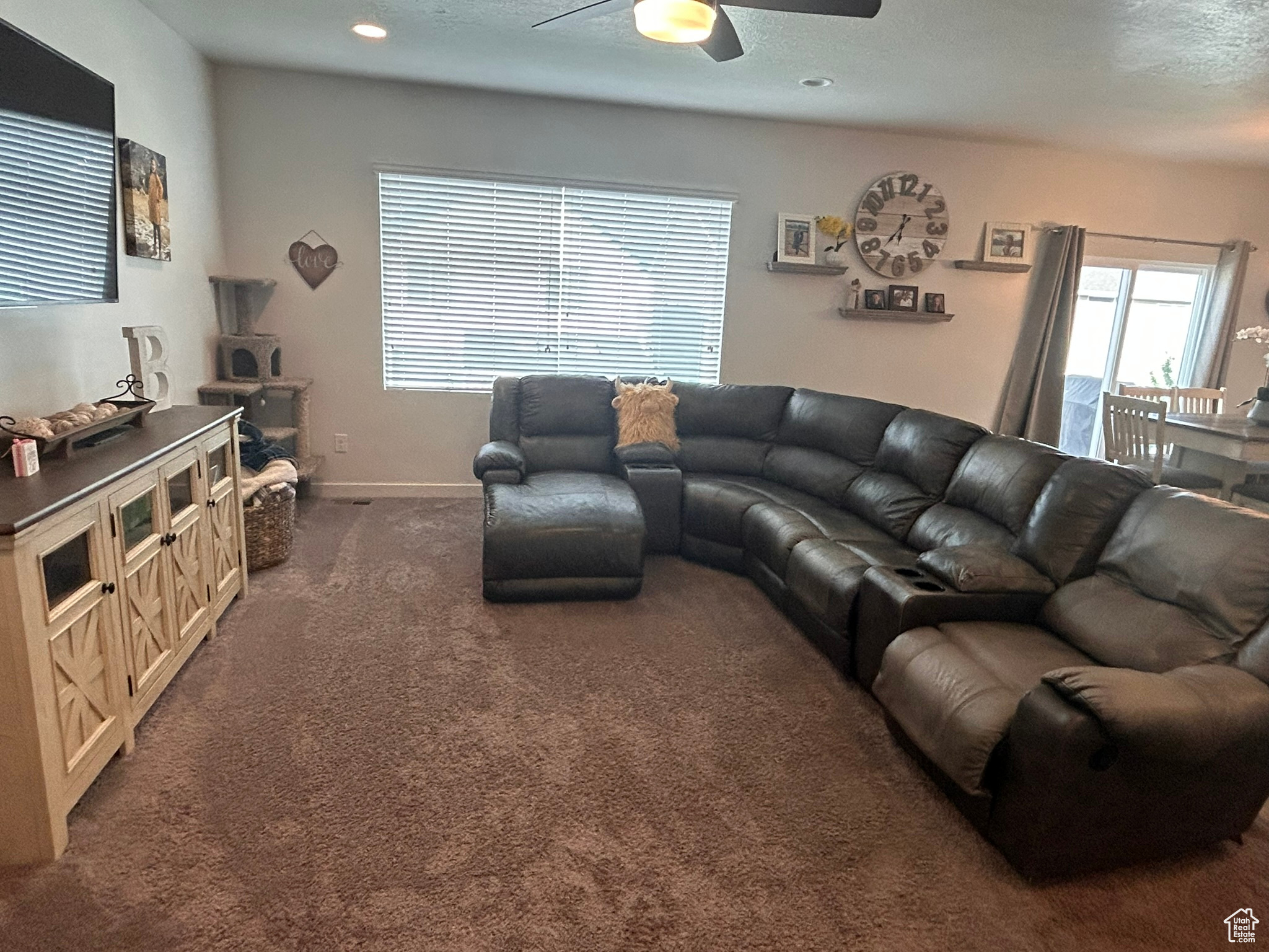 Living room featuring ceiling fan and dark carpet