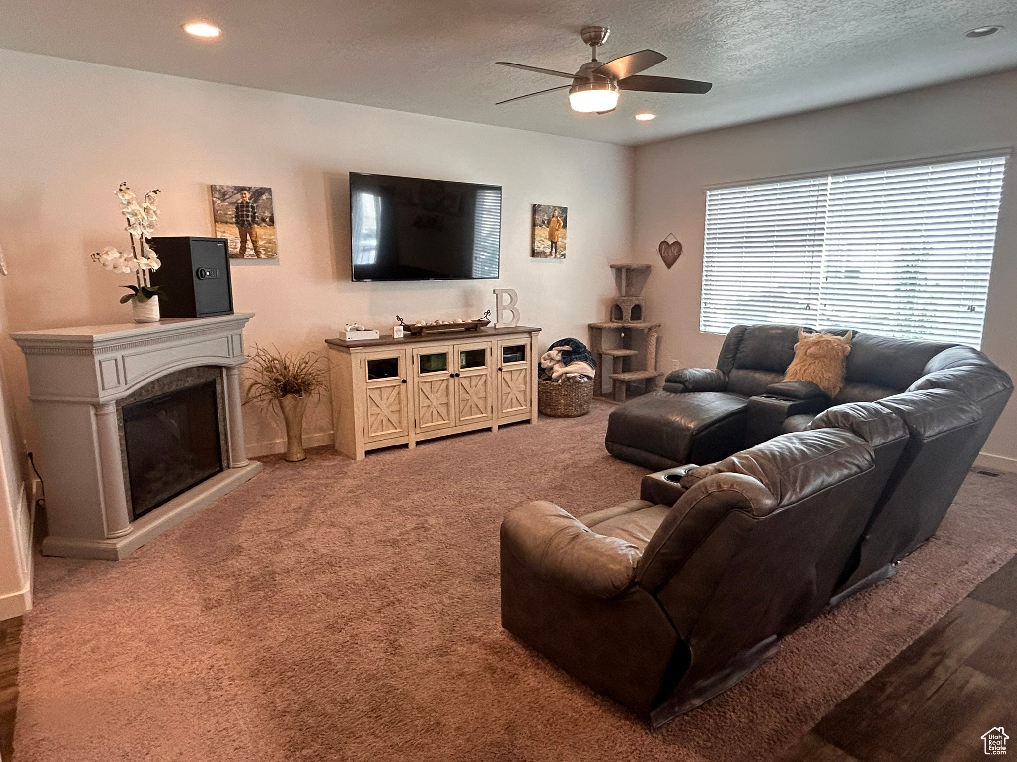 Living room with plenty of natural light, ceiling fan, carpet floors, and a textured ceiling