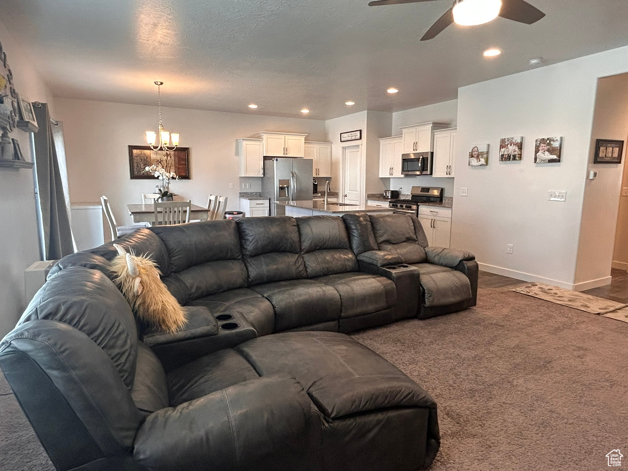 Living room with sink, carpet floors, and ceiling fan with notable chandelier