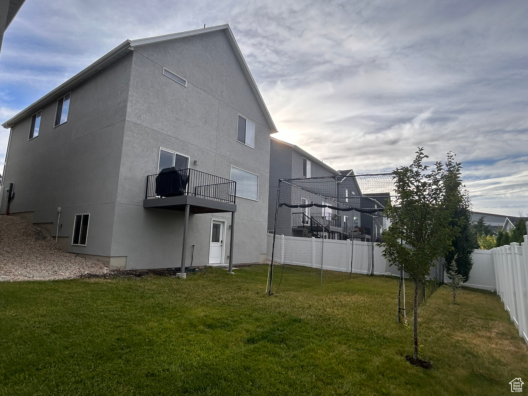 Rear view of house featuring a balcony and a lawn