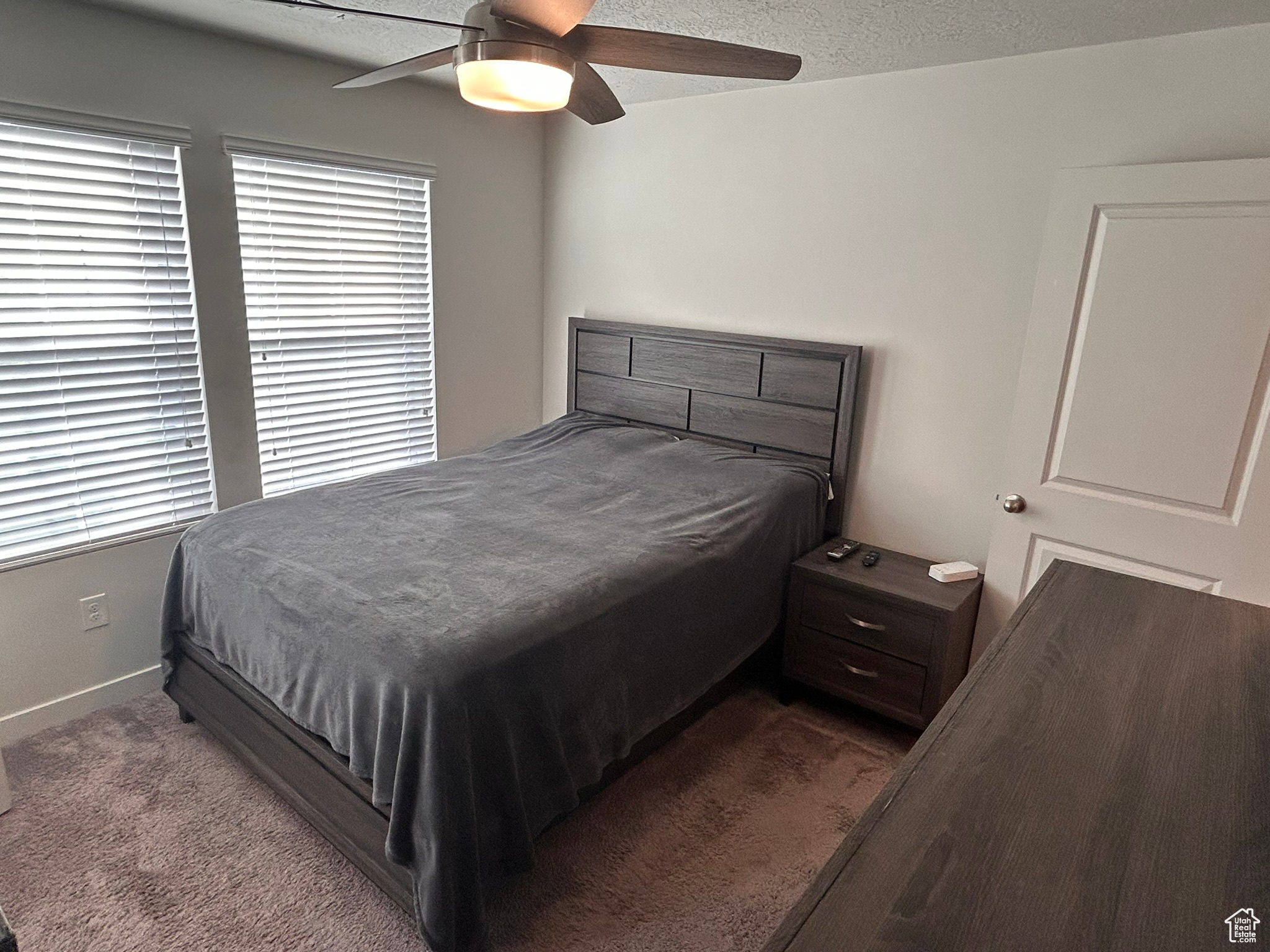 Carpeted bedroom with a textured ceiling and ceiling fan