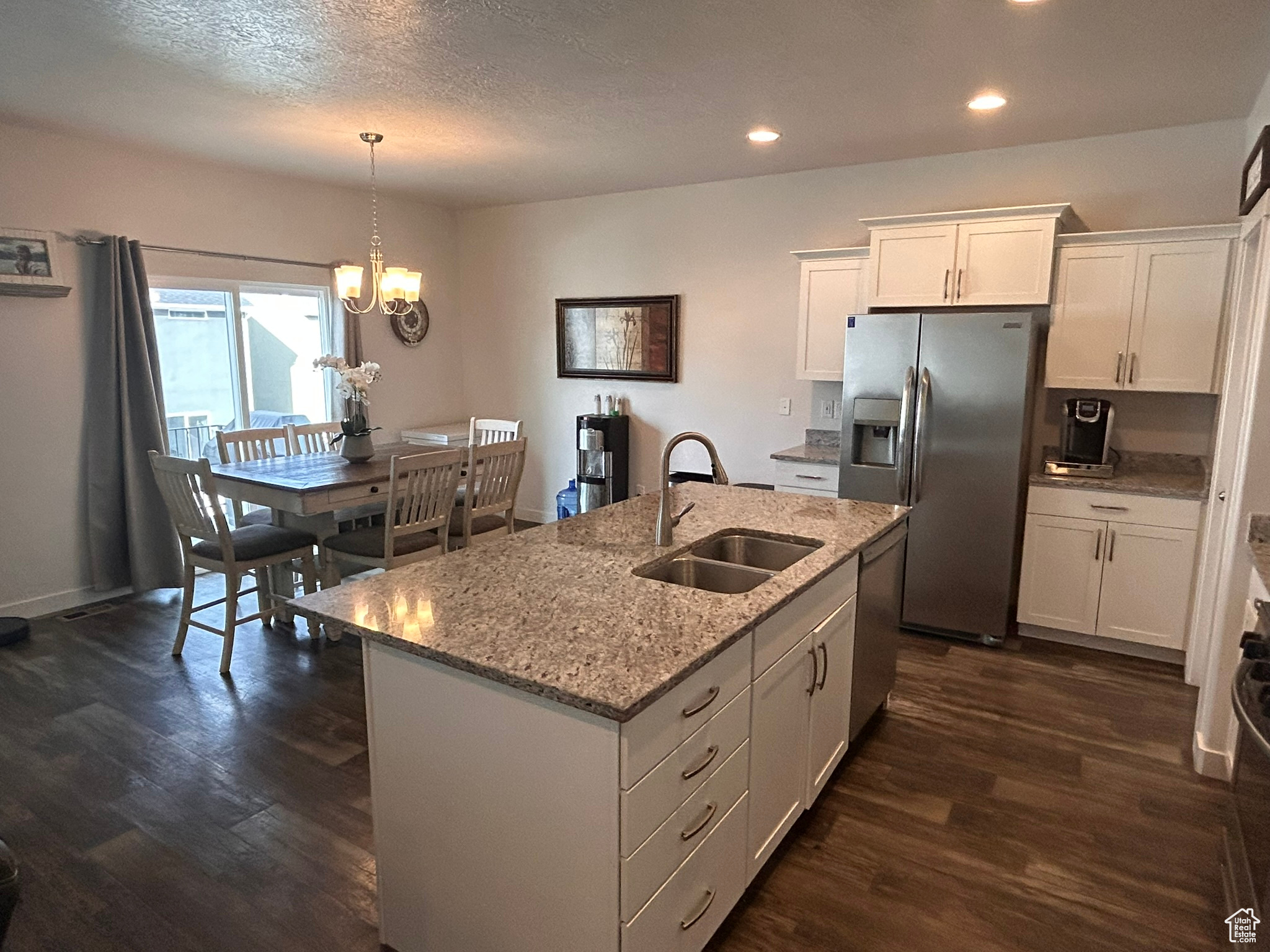 Kitchen featuring hanging light fixtures, an island with sink, white cabinets, dark hardwood / wood-style floors, and sink