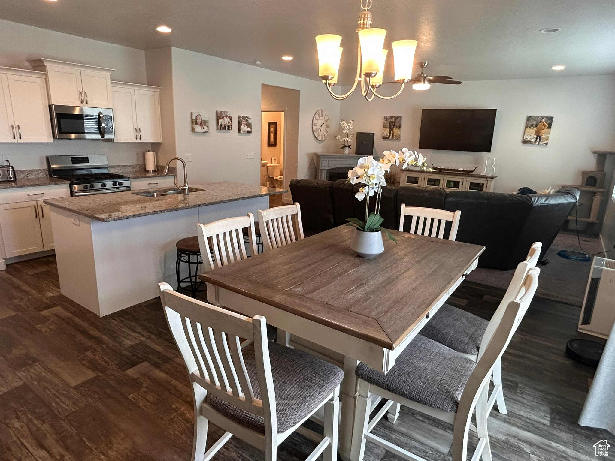 Dining room with sink, ceiling fan with notable chandelier, and dark wood-type flooring