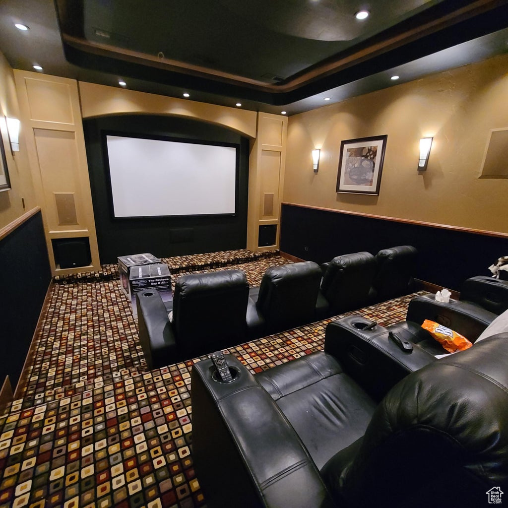 Incredible home cinema room featuring carpet and a tray ceiling.