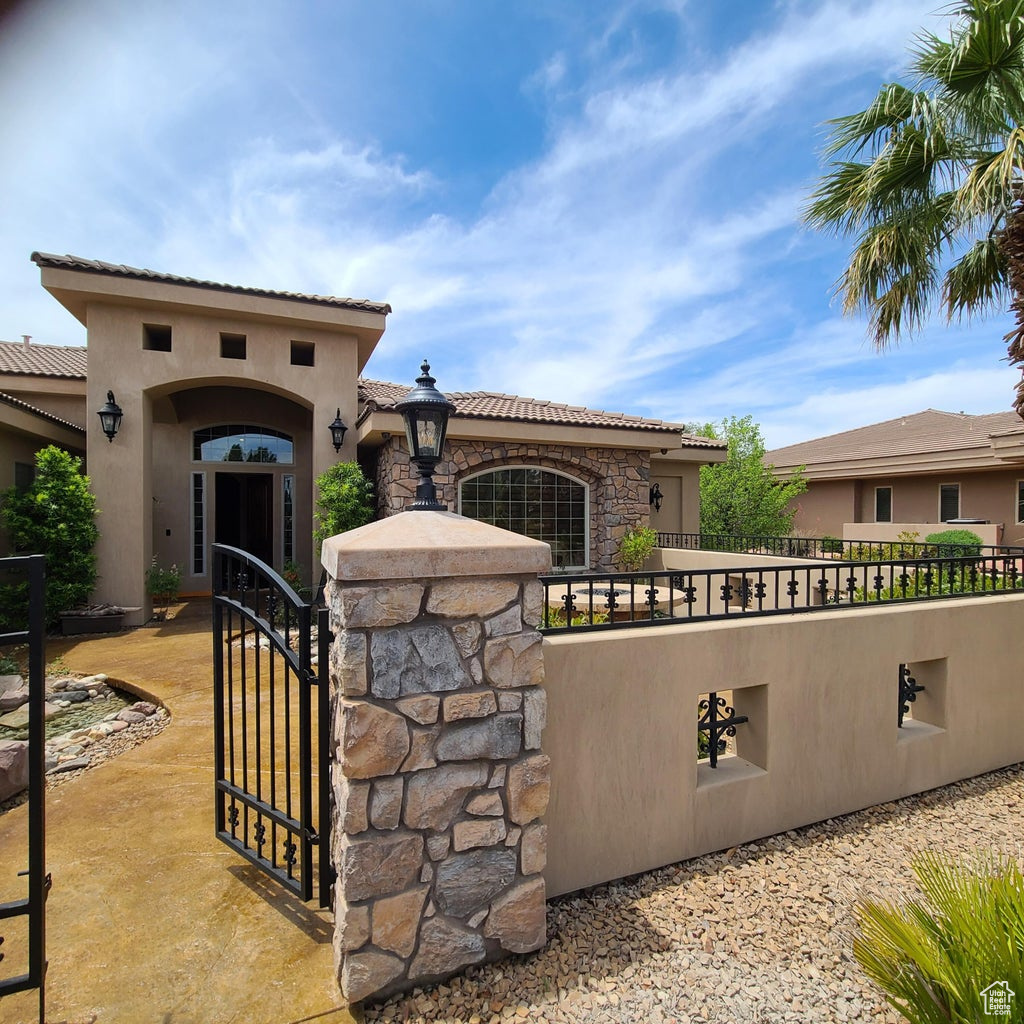 Mediterranean style house featuring mature landscaping, courtyard entrance and front lawn.