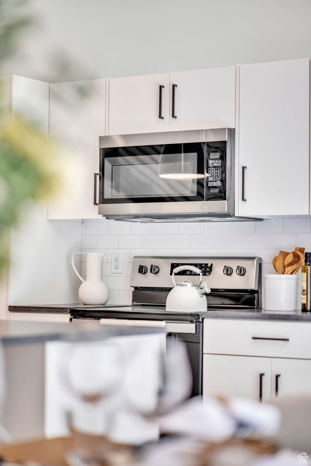 Kitchen featuring stainless steel appliances, tasteful backsplash, and white cabinetry