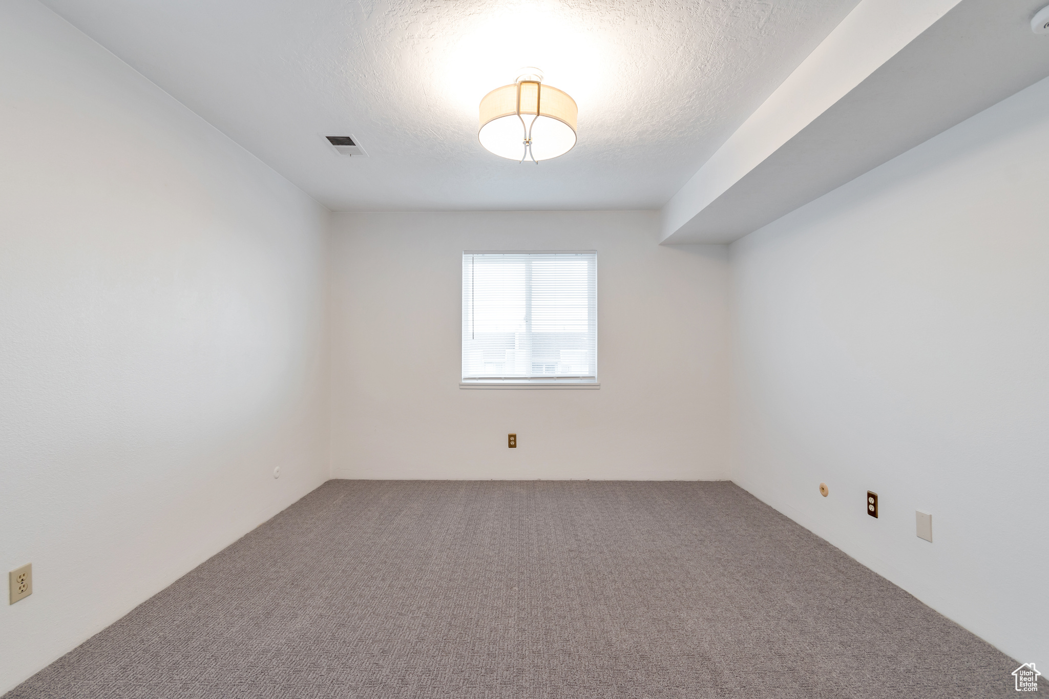 Carpeted empty room with a textured ceiling