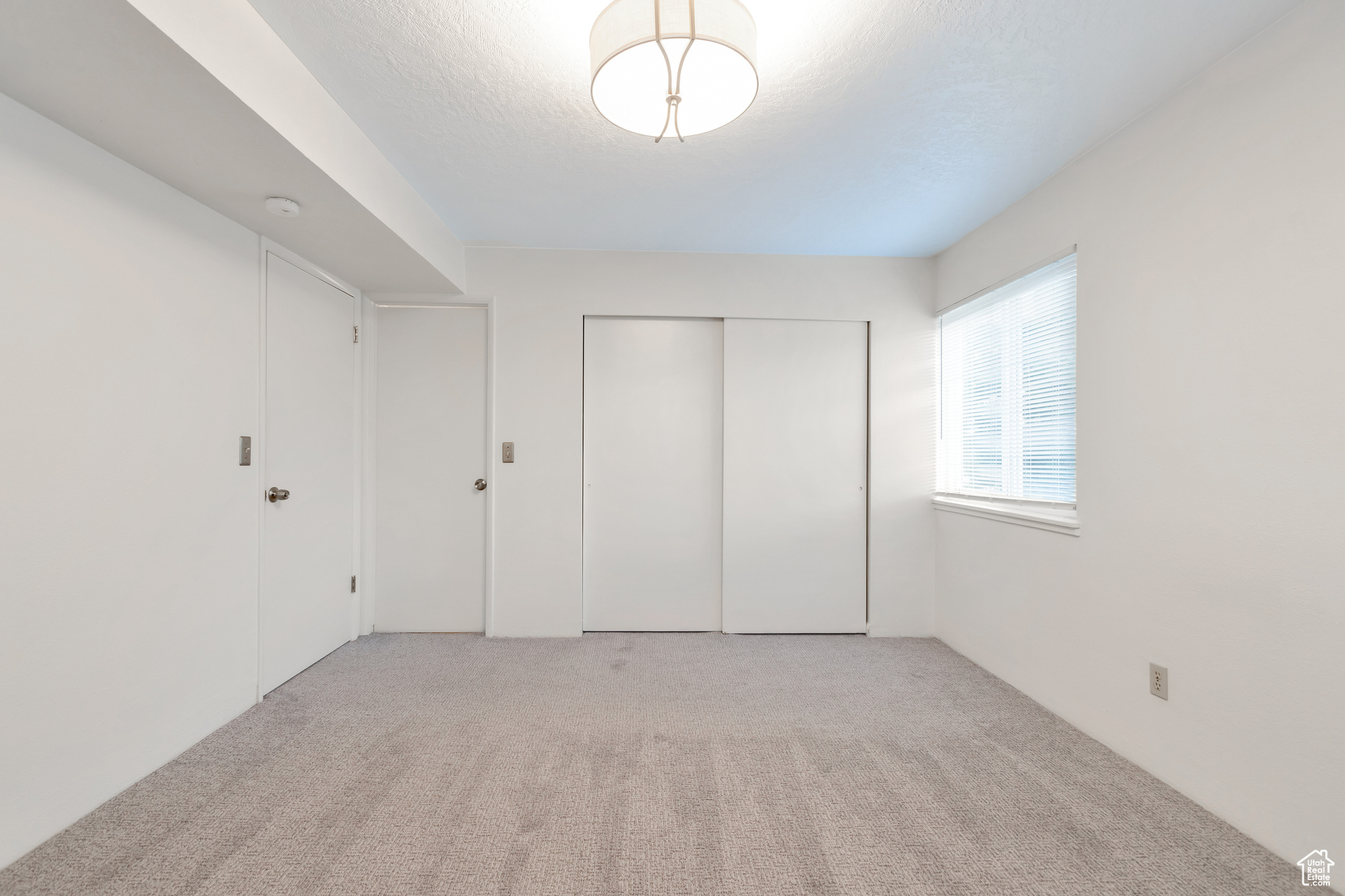 Unfurnished bedroom with light colored carpet and a closet