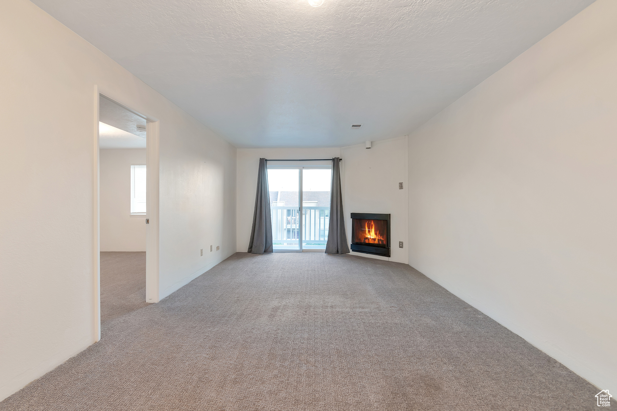 Unfurnished living room with a textured ceiling and carpet floors