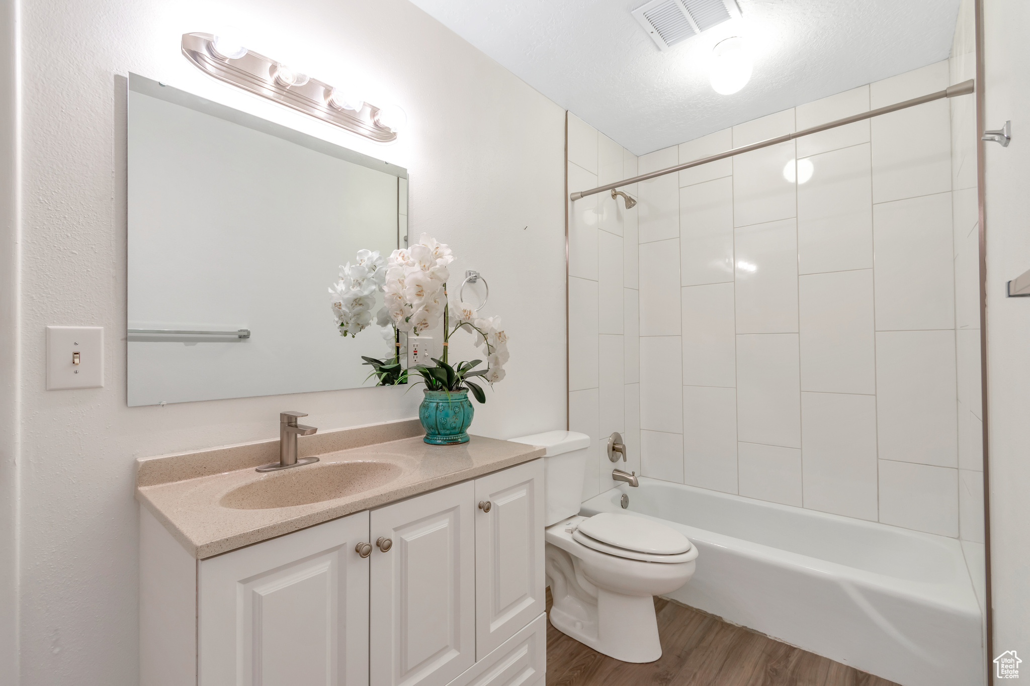 Full bathroom featuring tiled shower / bath, toilet, hardwood / wood-style flooring, and vanity