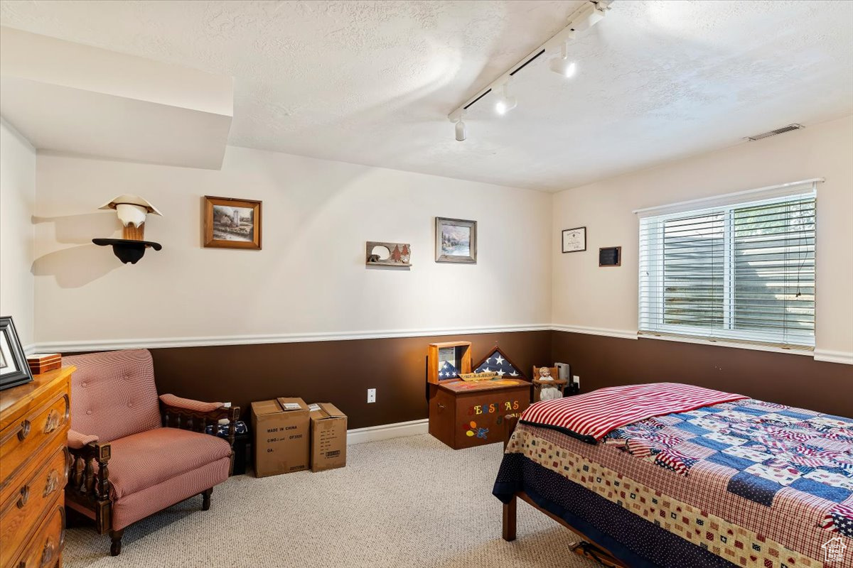 Bedroom with a textured ceiling, track lighting, and carpet flooring