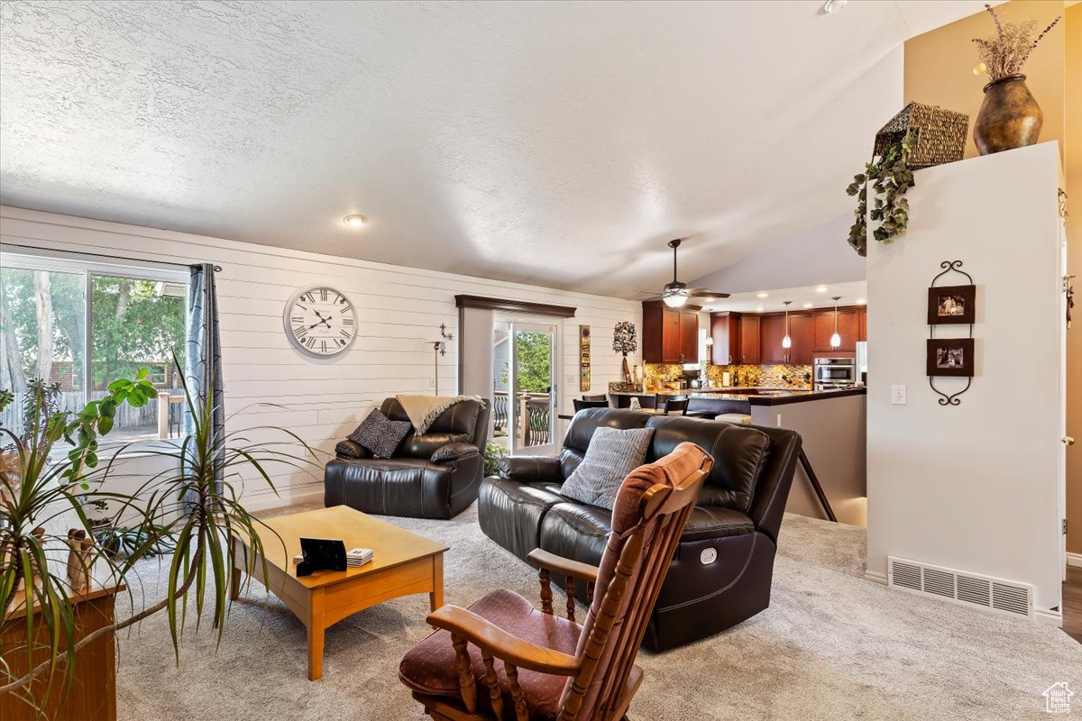 Carpeted living room with a wealth of natural light, ceiling fan, a textured ceiling, and lofted ceiling